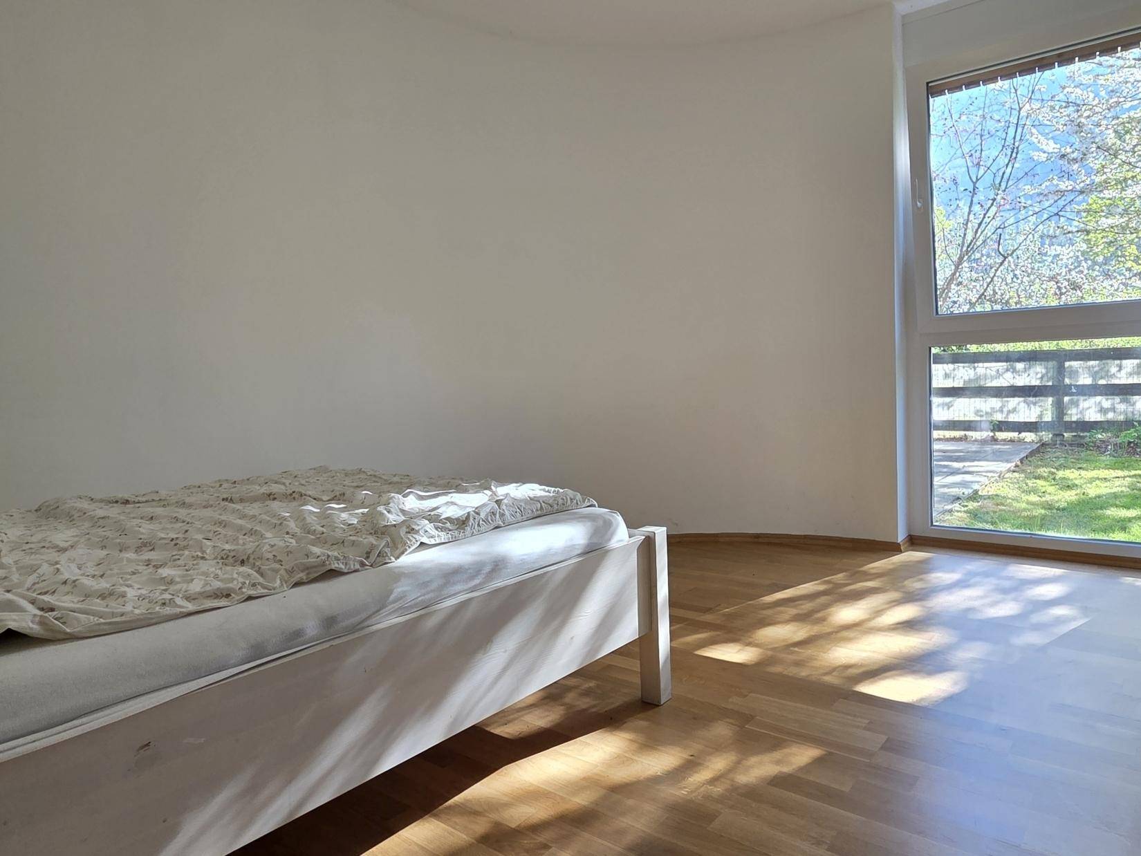 Helles Schlafzimmer mit Einzelbett, großem Fenster und viel natürlichem Lichteinfall.