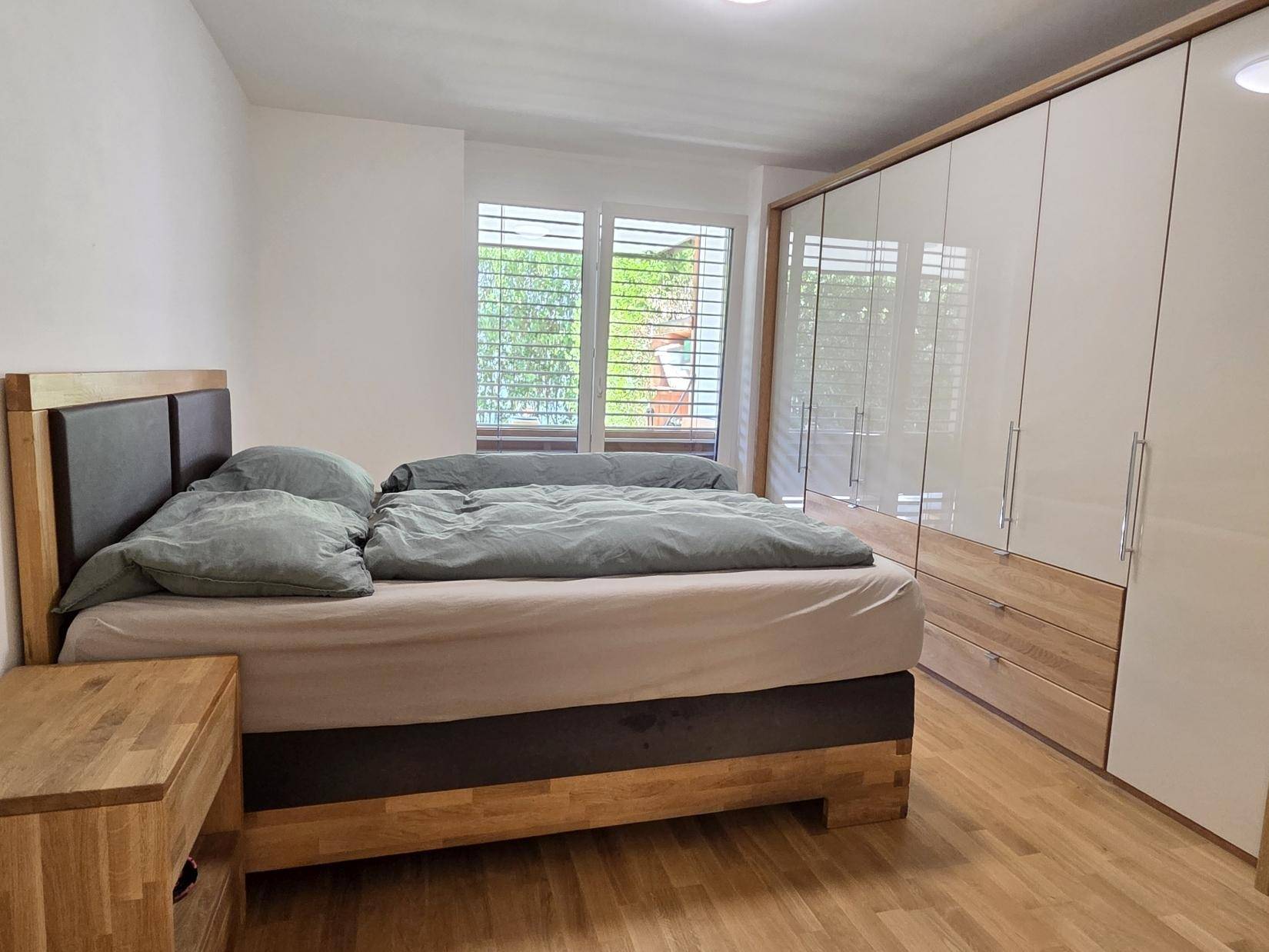 Helles Schlafzimmer mit Doppelbett, Holzmöbeln und großem weißen Kleiderschrank.