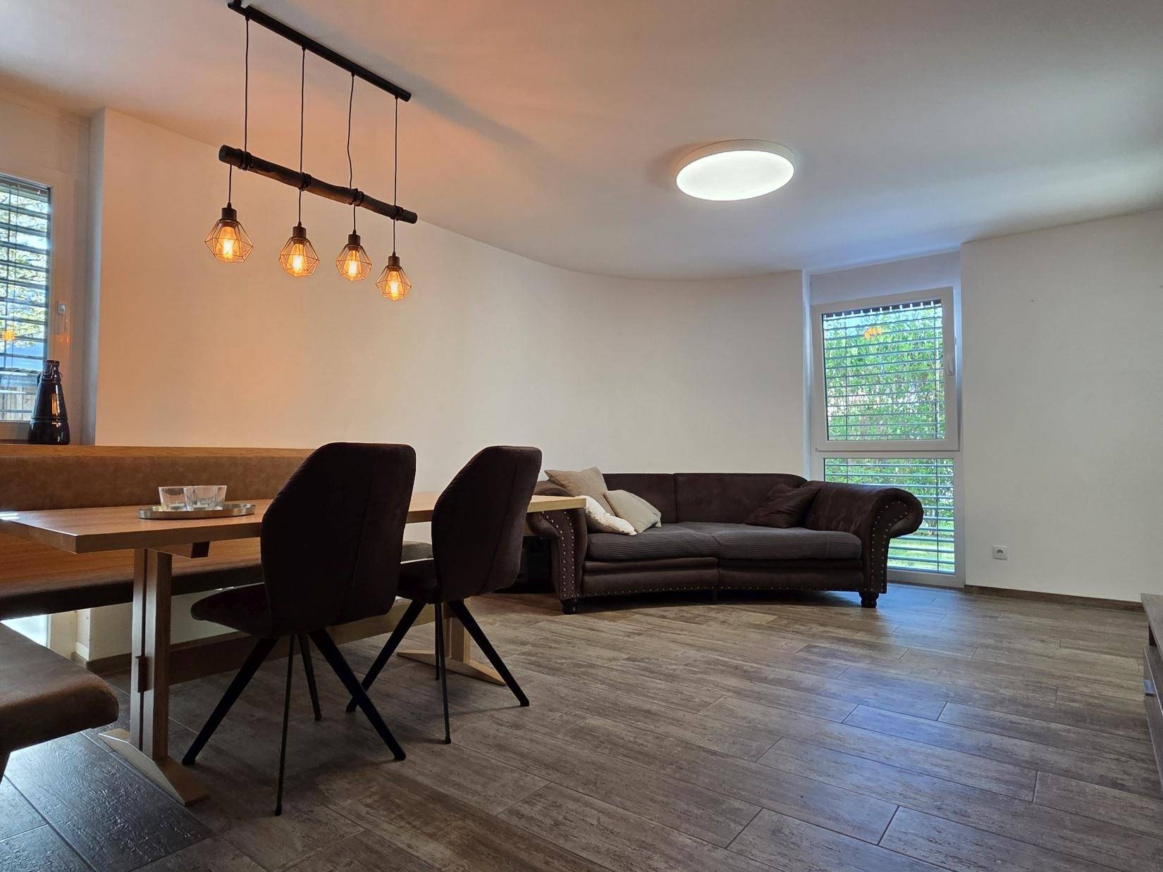 Gemütlicher Wohn- und Essbereich mit Holzboden, bequemer Sitzbank und Sofa.