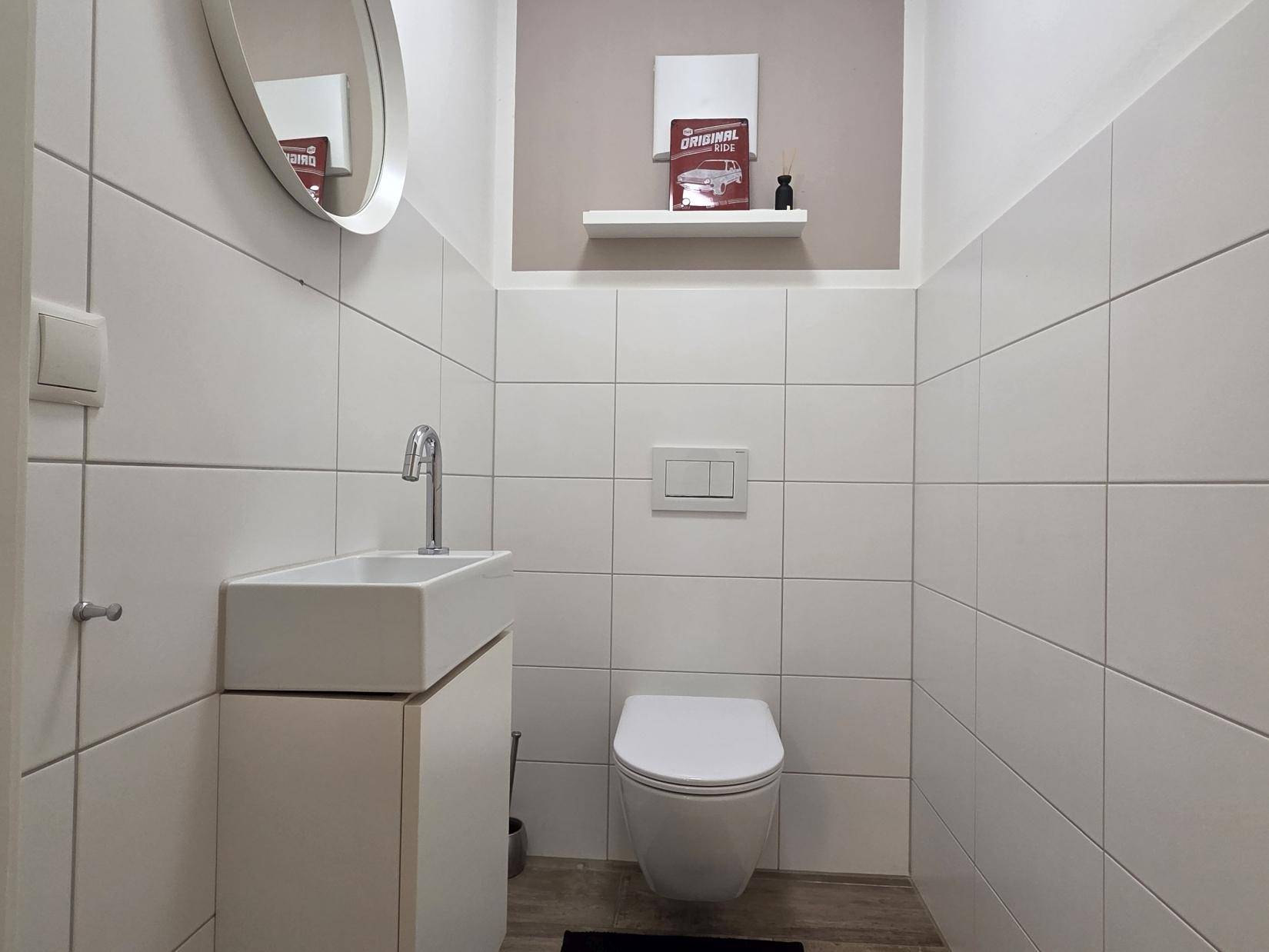 Kleines Gäste-WC mit wandhängender Toilette und modernem Handwaschbecken.