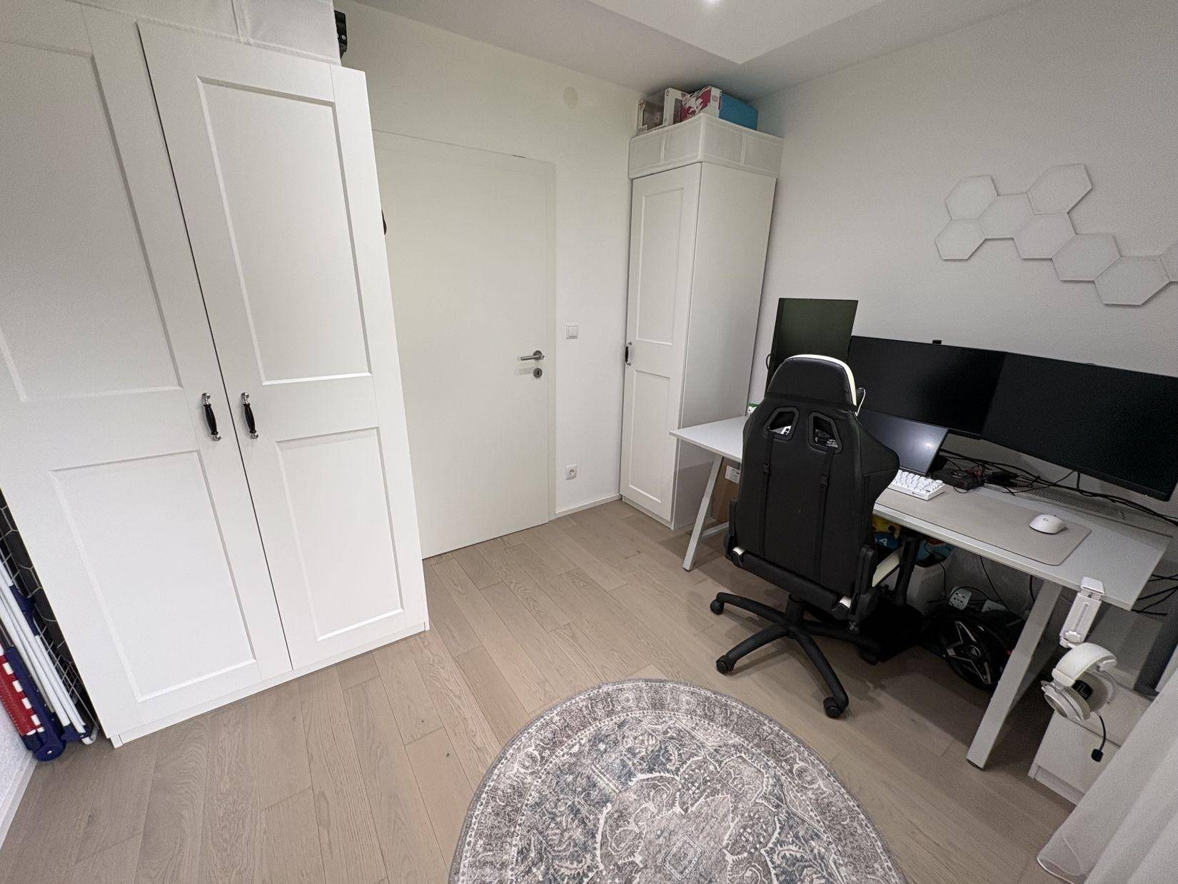 Funktionales Arbeitszimmer mit zwei Schreibtischen, Stauraum und Holzboden.