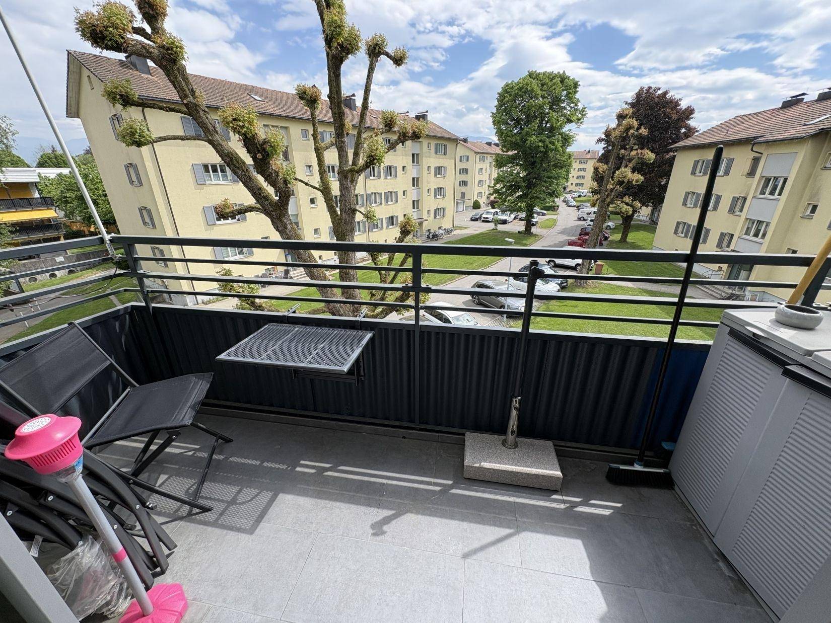 Möblierter Balkon mit Blick auf die umliegenden Gebäude und Bäume.