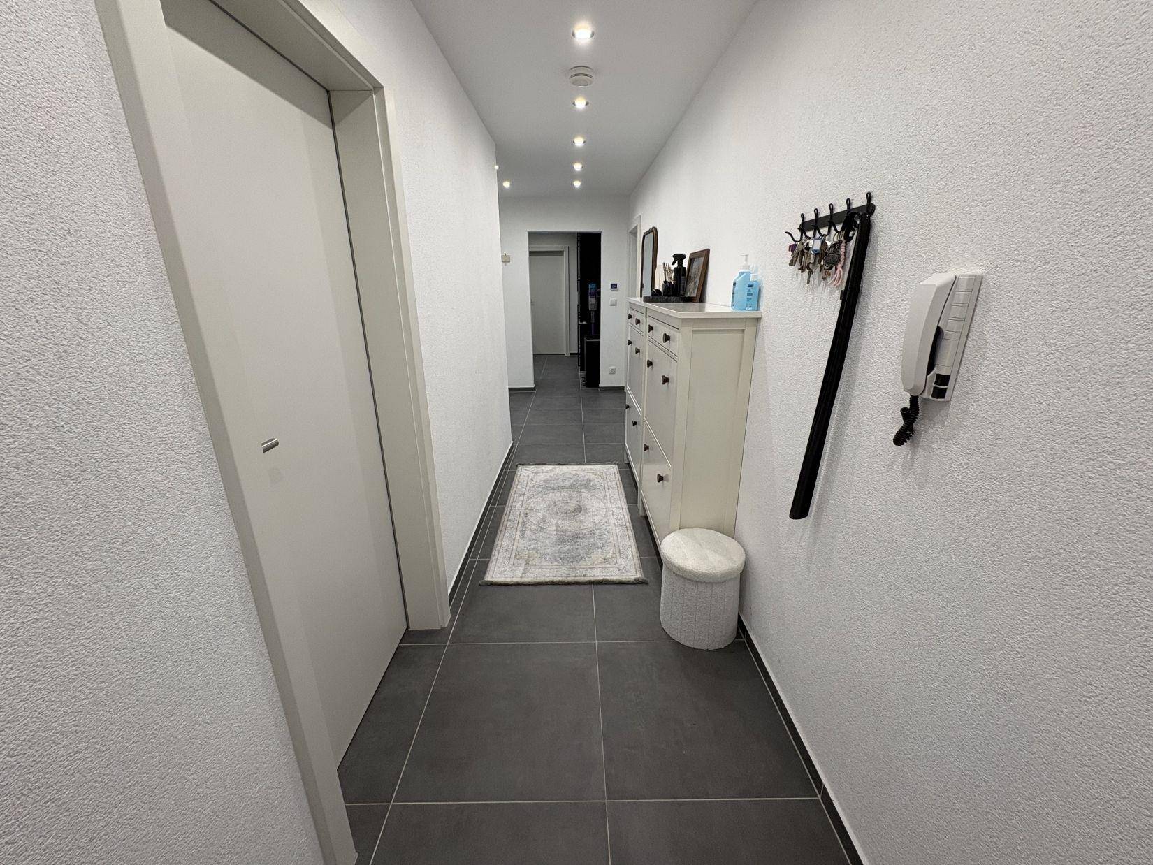 Heller Flur mit Fliesenboden, Spiegel und Garderobe.