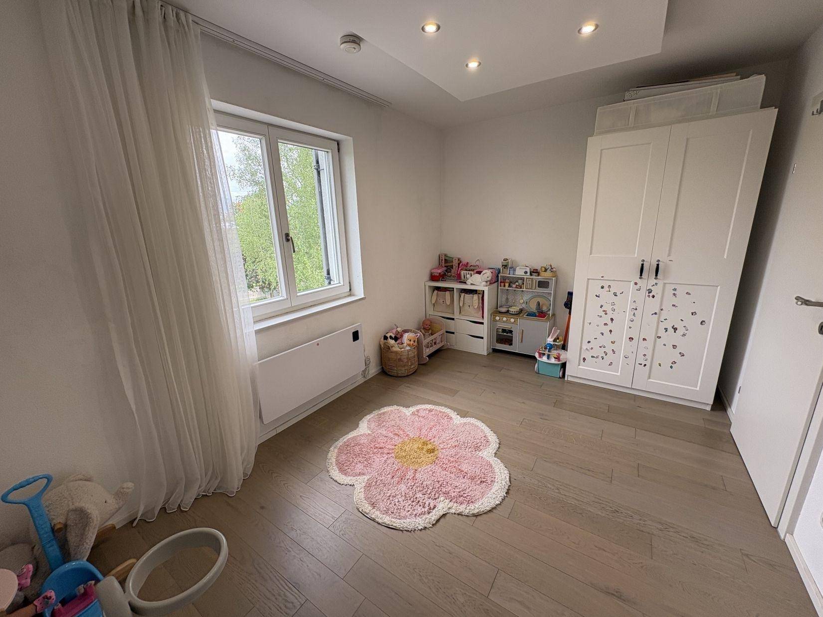 Helles Kinderzimmer mit Spielzeug, Schrank und Fenster mit Blick ins Grüne.