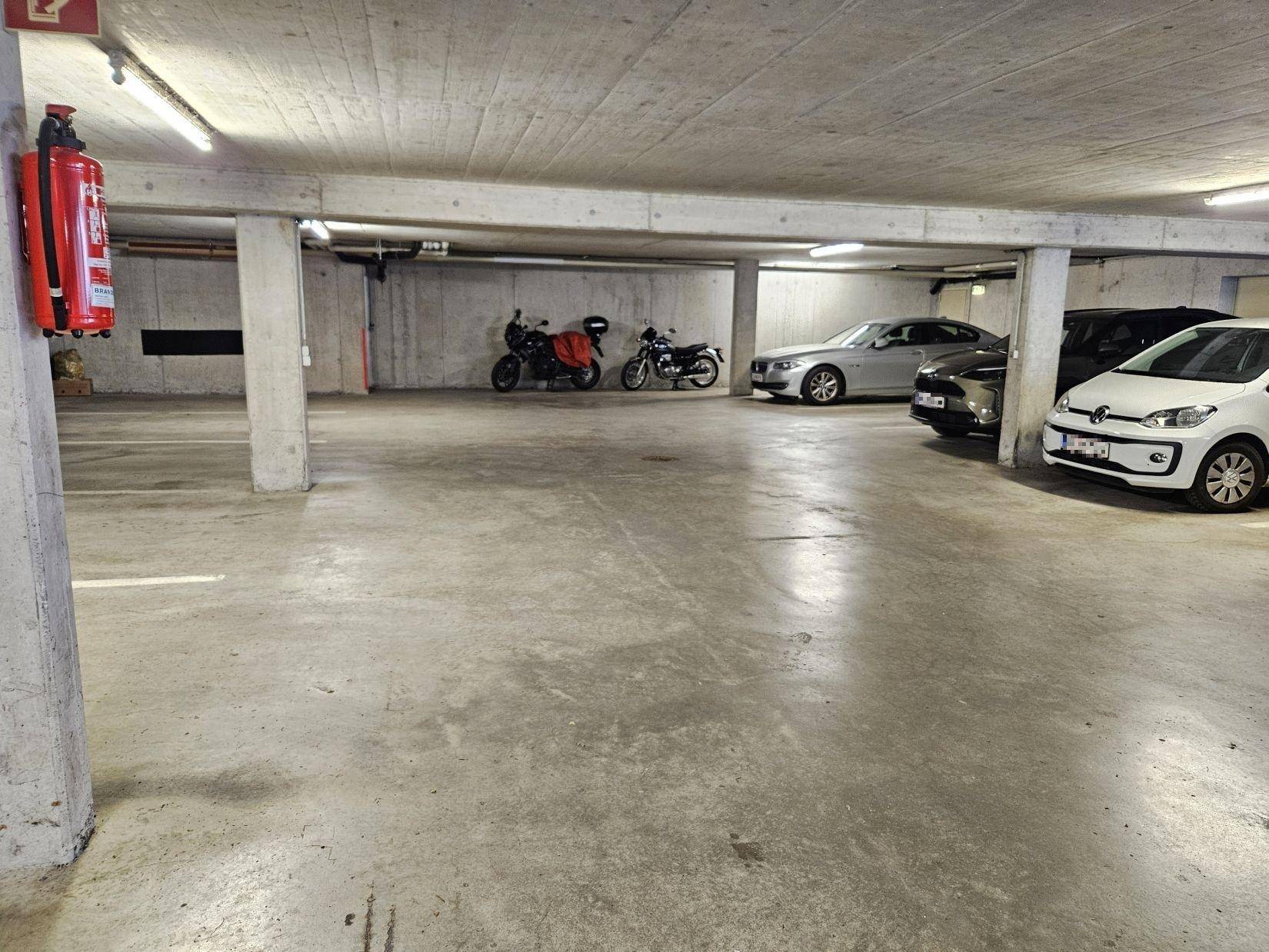 Geräumige Tiefgarage mit mehreren Stellplätzen für Autos und Motorräder.