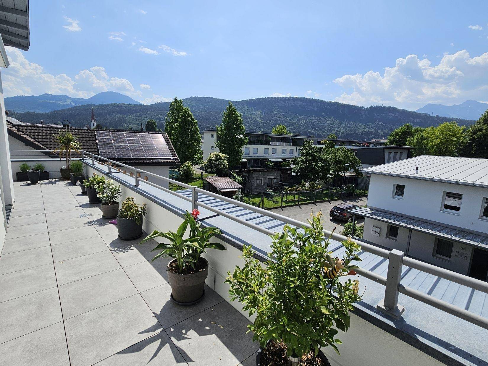 Weitläufige Dachterrasse mit vielen Pflanzen und einem Panoramablick auf die umliegende Berglandschaft.