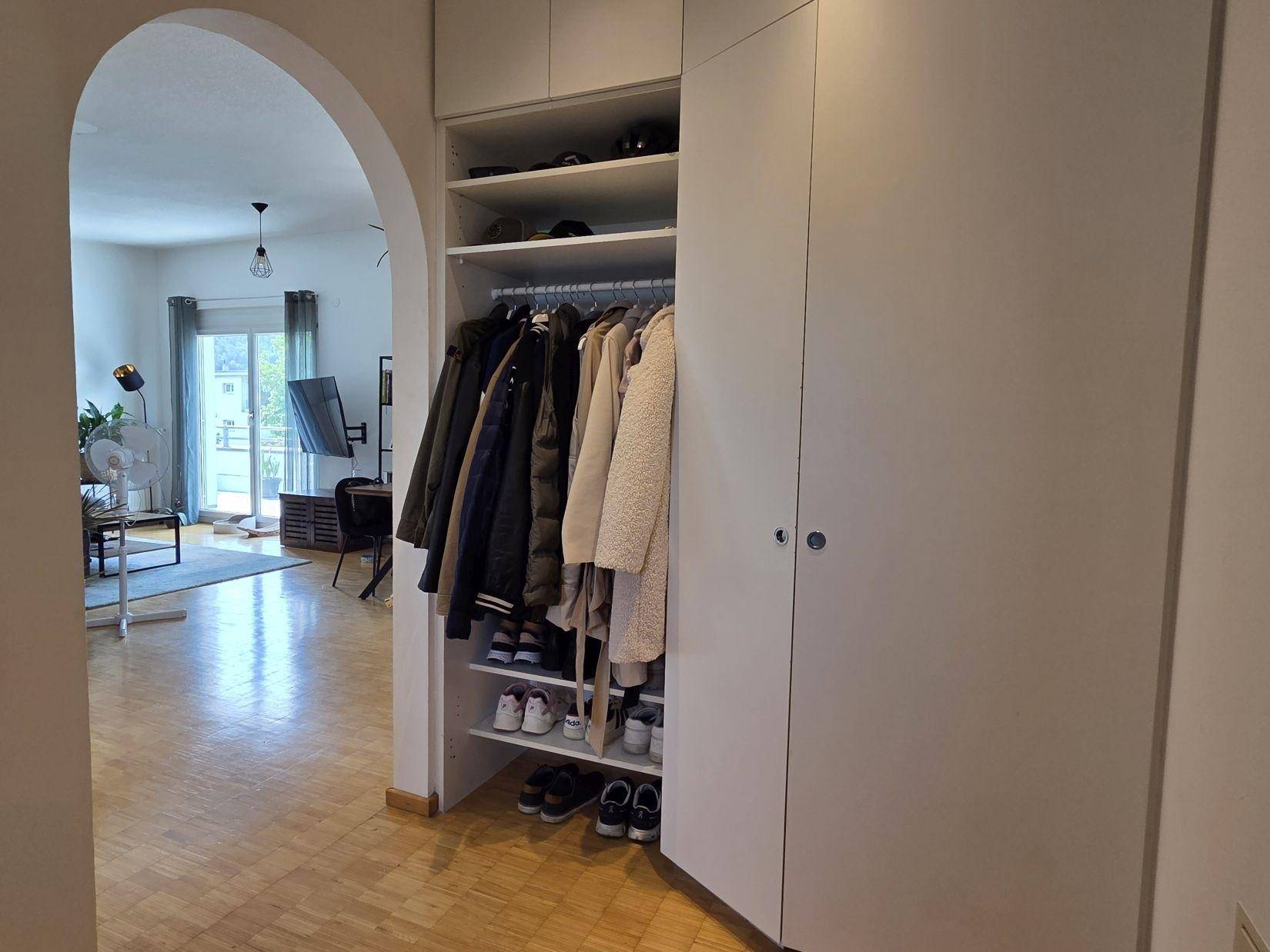 Eingangsbereich mit integriertem Garderobenschrank und Blick in den offenen Wohnbereich.