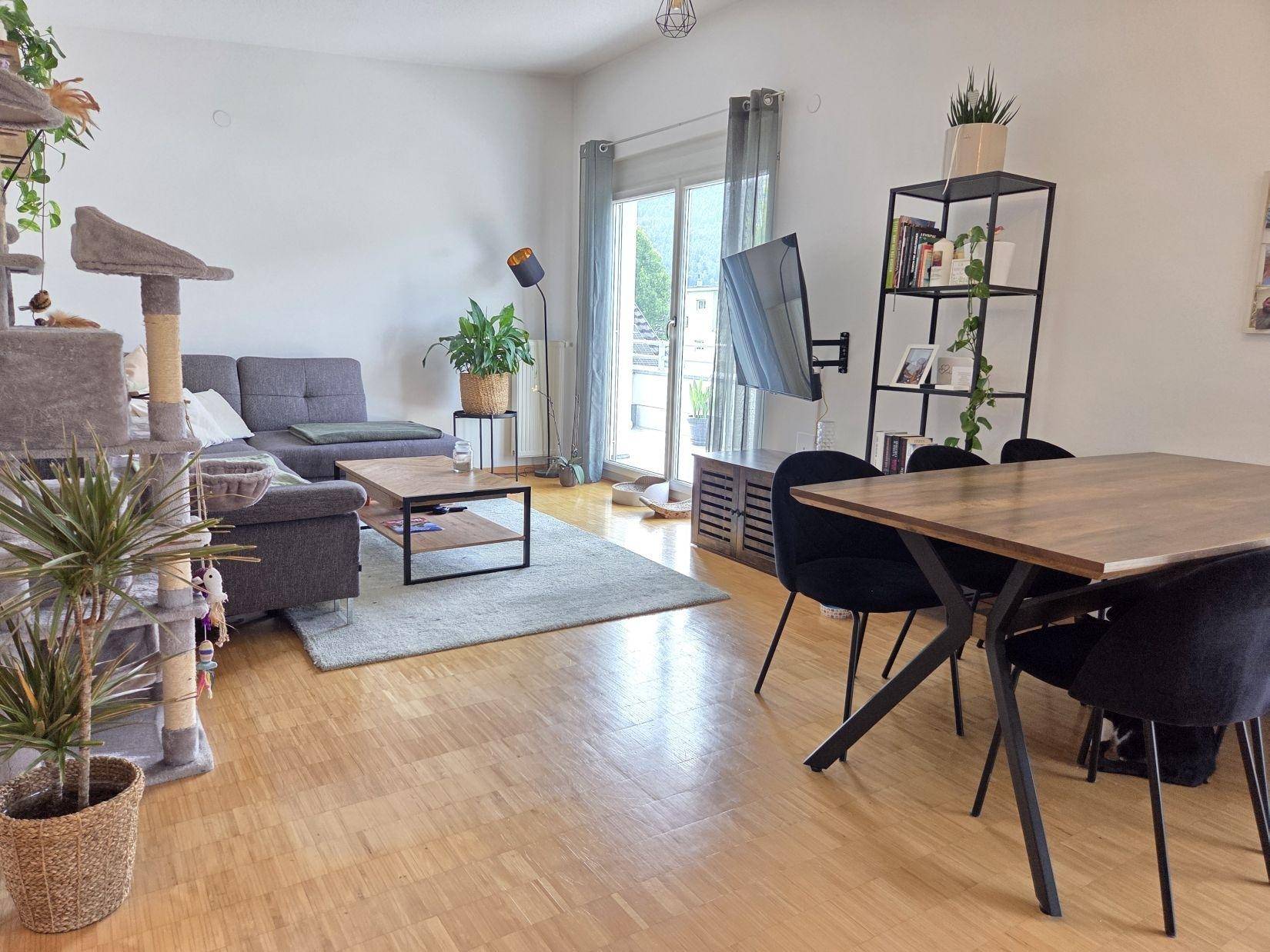 Heller Wohn- und Essbereich mit Holzparkett, modernem Sofa und Zugang zur Terrasse.