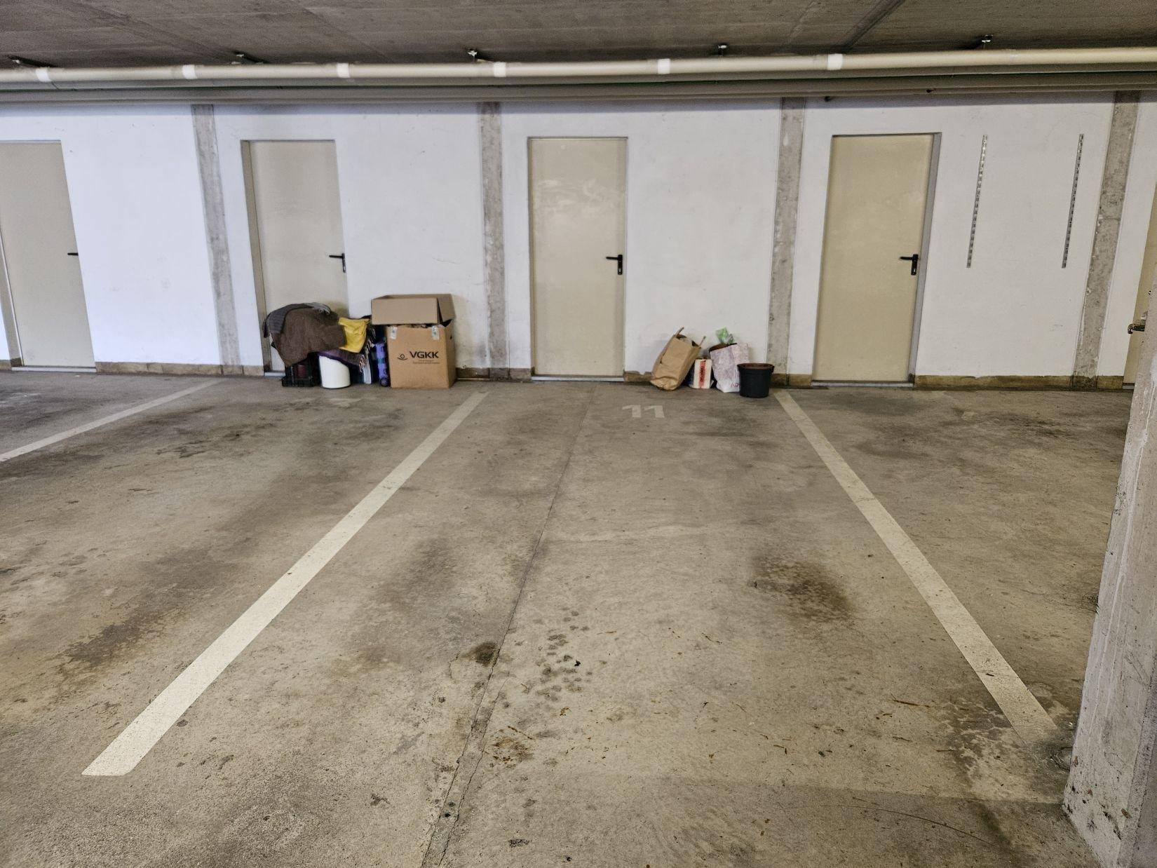 Tiefgaragenstellplätze mit Betonboden und Lagermöglichkeiten im Hintergrund.