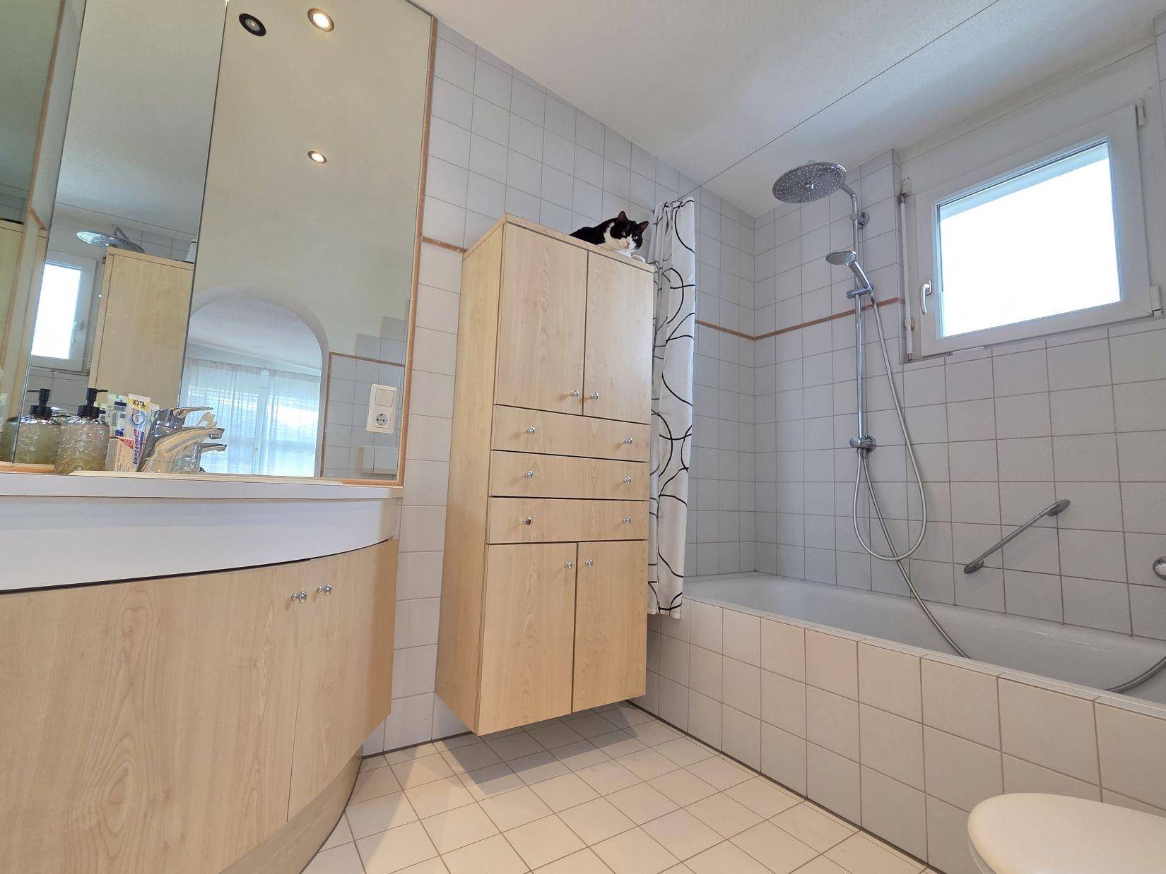 Gefliestes Badezimmer mit Badewanne, Dusche, Waschbecken und einem Fenster für Tageslicht.