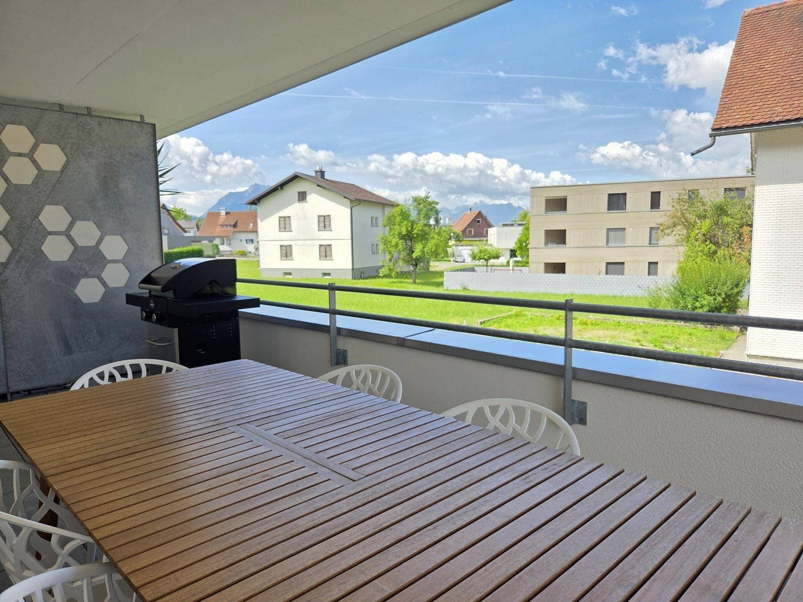 Balkon mit Panoramablick auf die grüne Landschaft und die majestätischen Berge in der Ferne.