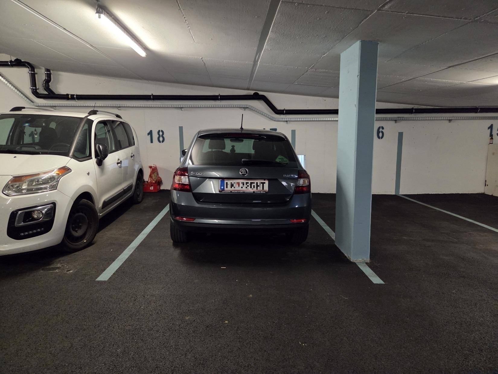 Tiefgarage mit markierten Stellplätzen und zwei geparkten Fahrzeugen.