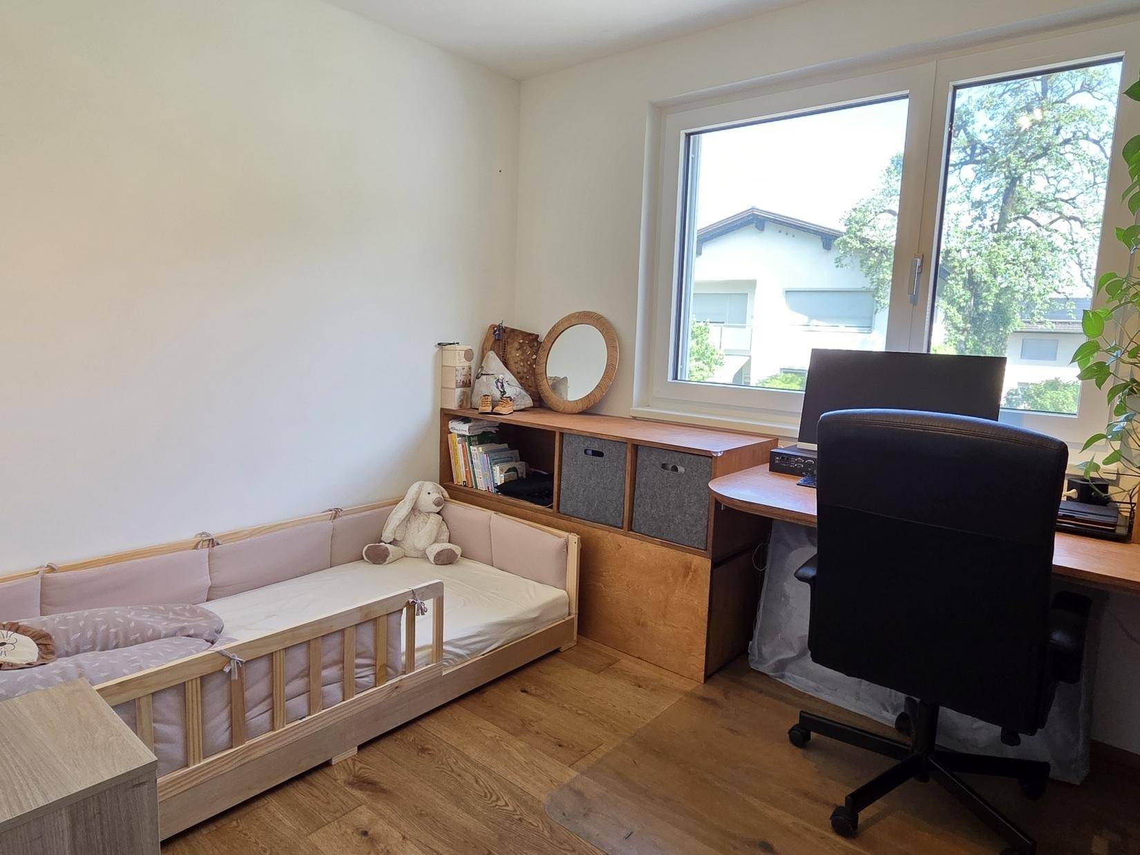 Kinderzimmer oder Gästezimmer mit kleinem Bett, Schreibtisch und hellem Fenster.