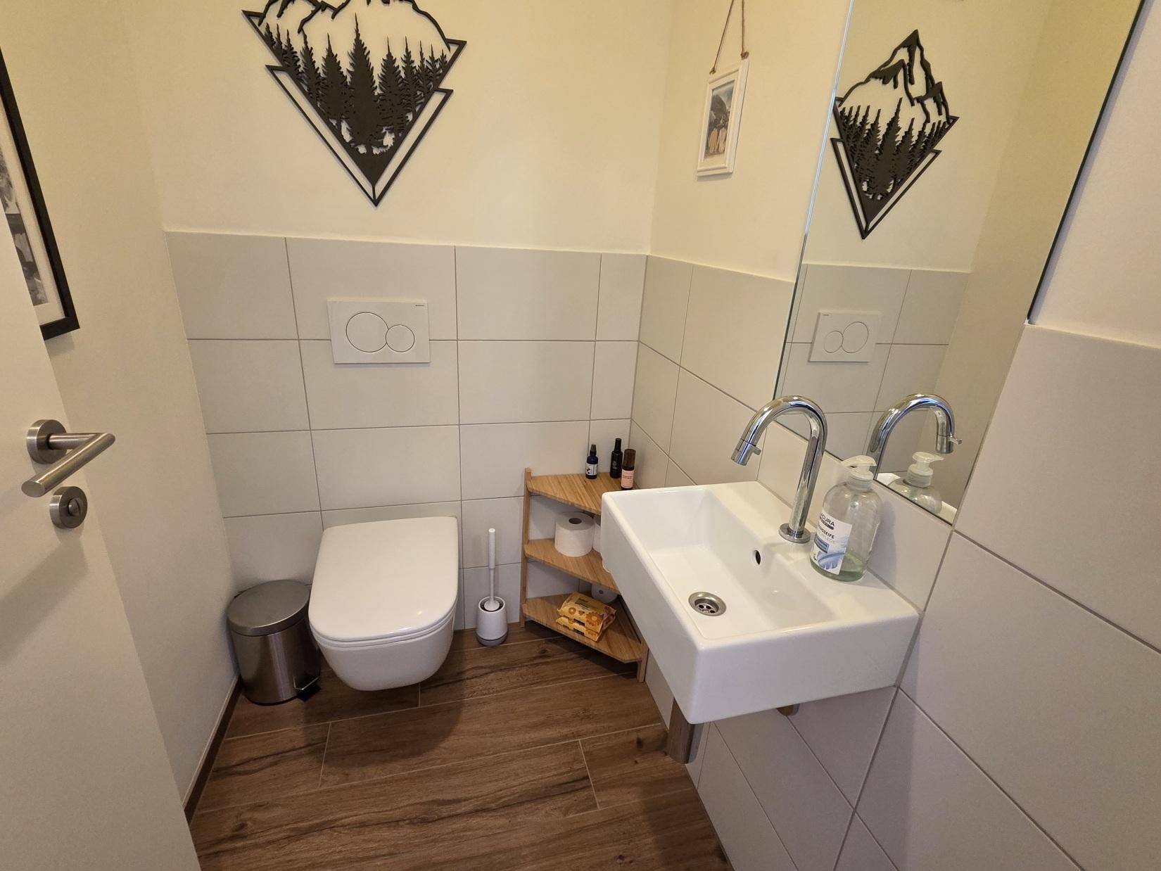 Praktisches Gäste-WC mit wandhängender Toilette, kleinem Waschbecken und Spiegel.