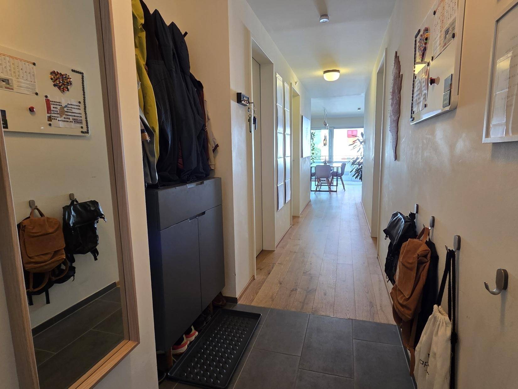 Eingangsbereich mit Spiegel, Schuhschrank und Garderobe, der in den Wohnbereich übergeht.