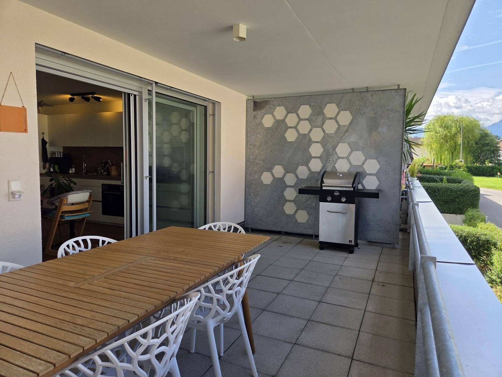 Geräumiger Balkon mit Esstisch, Grill und Blick auf die umliegende Landschaft und Berge.