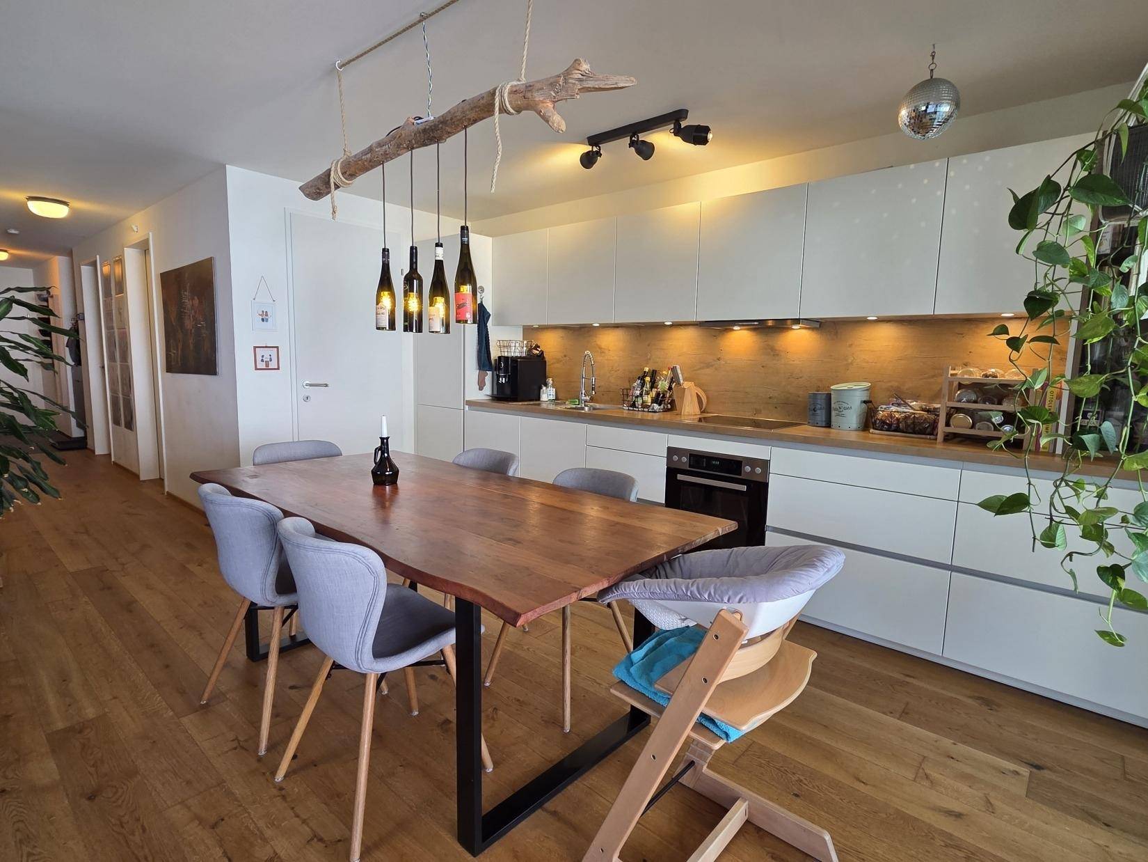 Helle Einbauküche mit Essbereich, modernen Geräten und Holzboden, ideal für Familien.