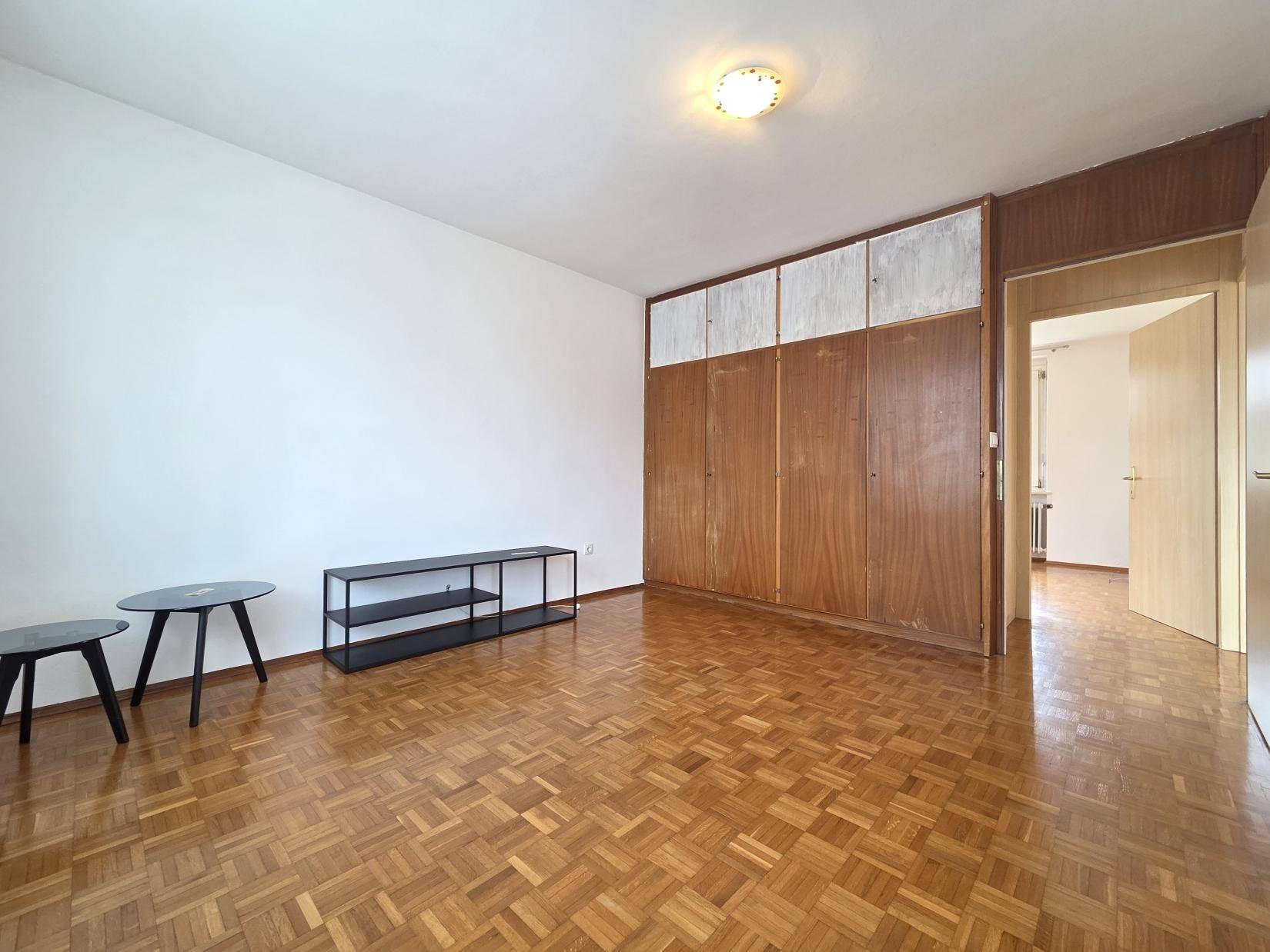 Geräumiges Zimmer mit Parkettboden und praktischen Einbauschränken aus Holz.
