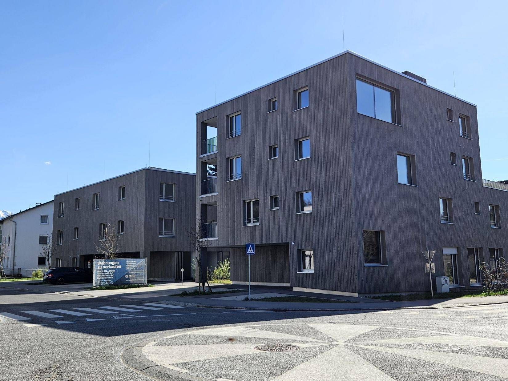 Ansicht der modernen Wohngebäude an einer Straßenecke unter blauem Himmel.
