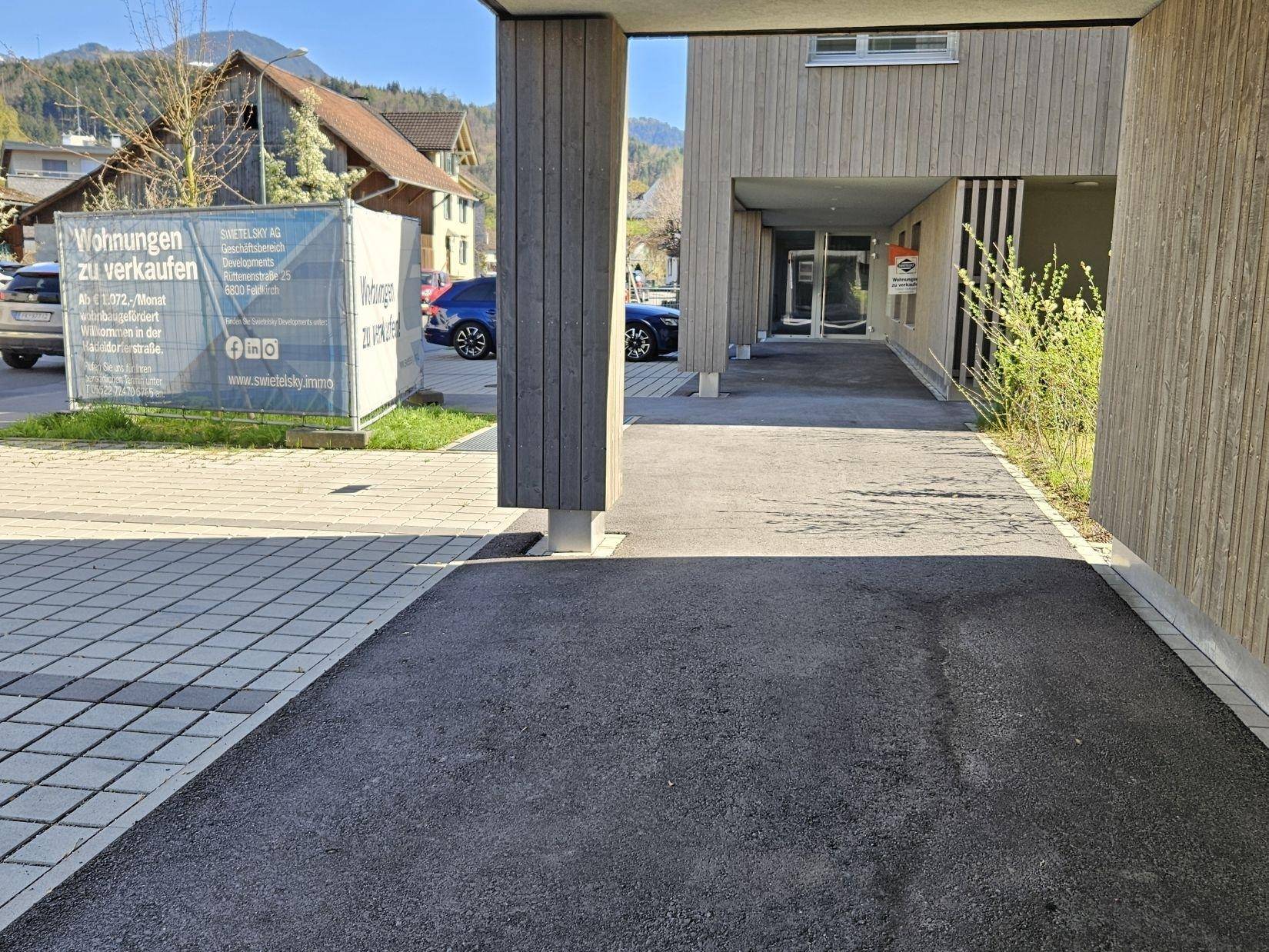 Eingangsbereich des Gebäudes mit Säule und einem Bauschild im Hintergrund.