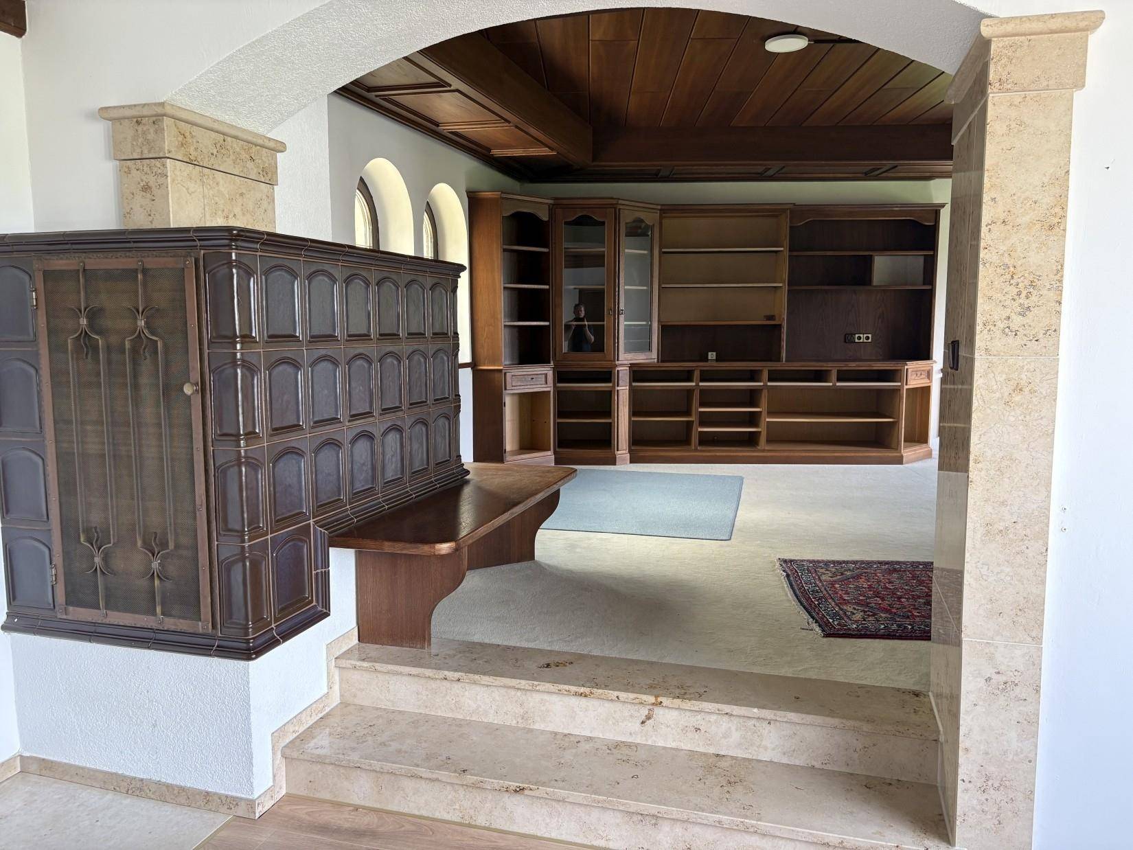 Eingangsbereich mit Steinstufen, Kachelofen und Blick in das angrenzende Wohnzimmer.