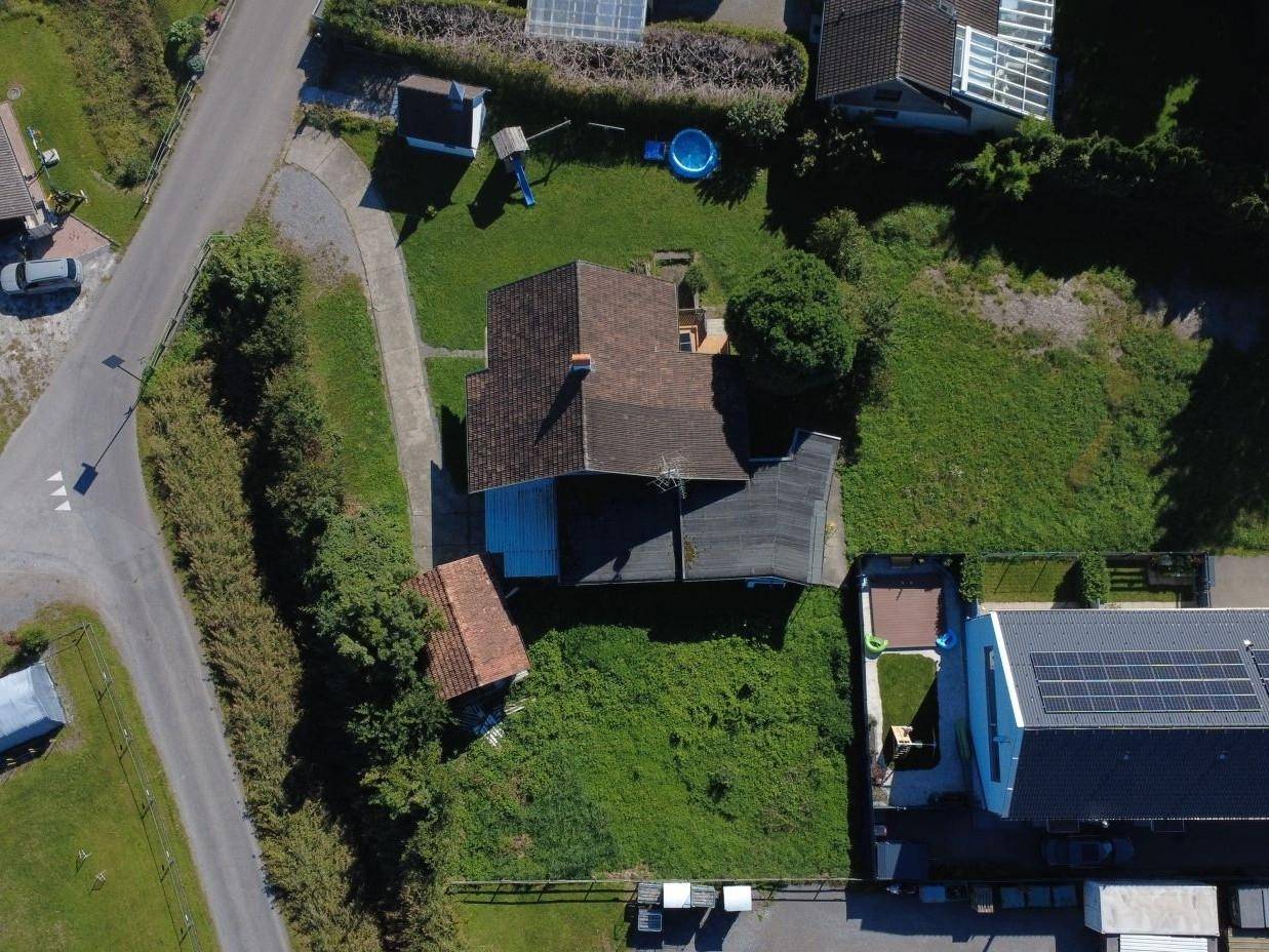 Luftaufnahme eines Grundstücks mit gelber Umrandung, umgeben von Wohngebäuden und einer Straße in ländlicher Umgebung.