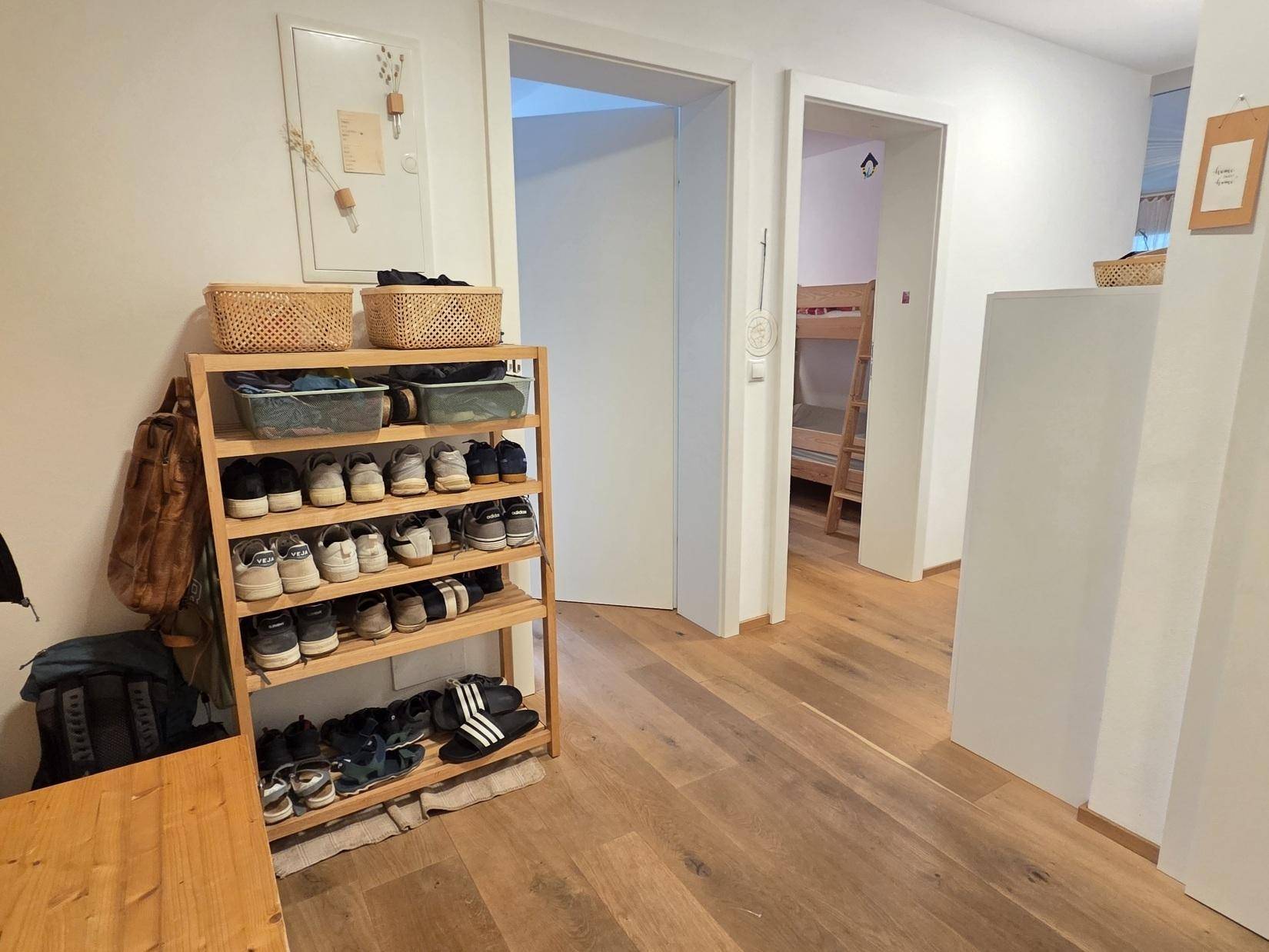 Flur mit Holzboden und Schuhregal, der zu weiteren Zimmern führt.