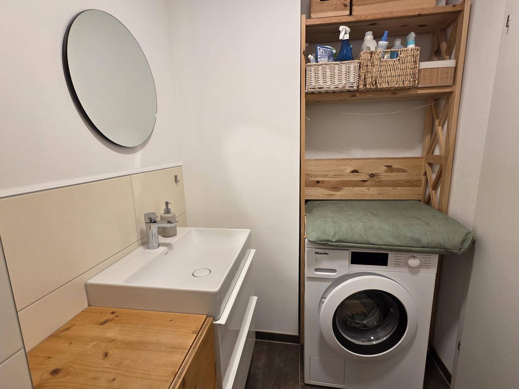 Kleiner Raum mit Waschbecken, WC und Waschmaschine, praktisch eingerichtet.