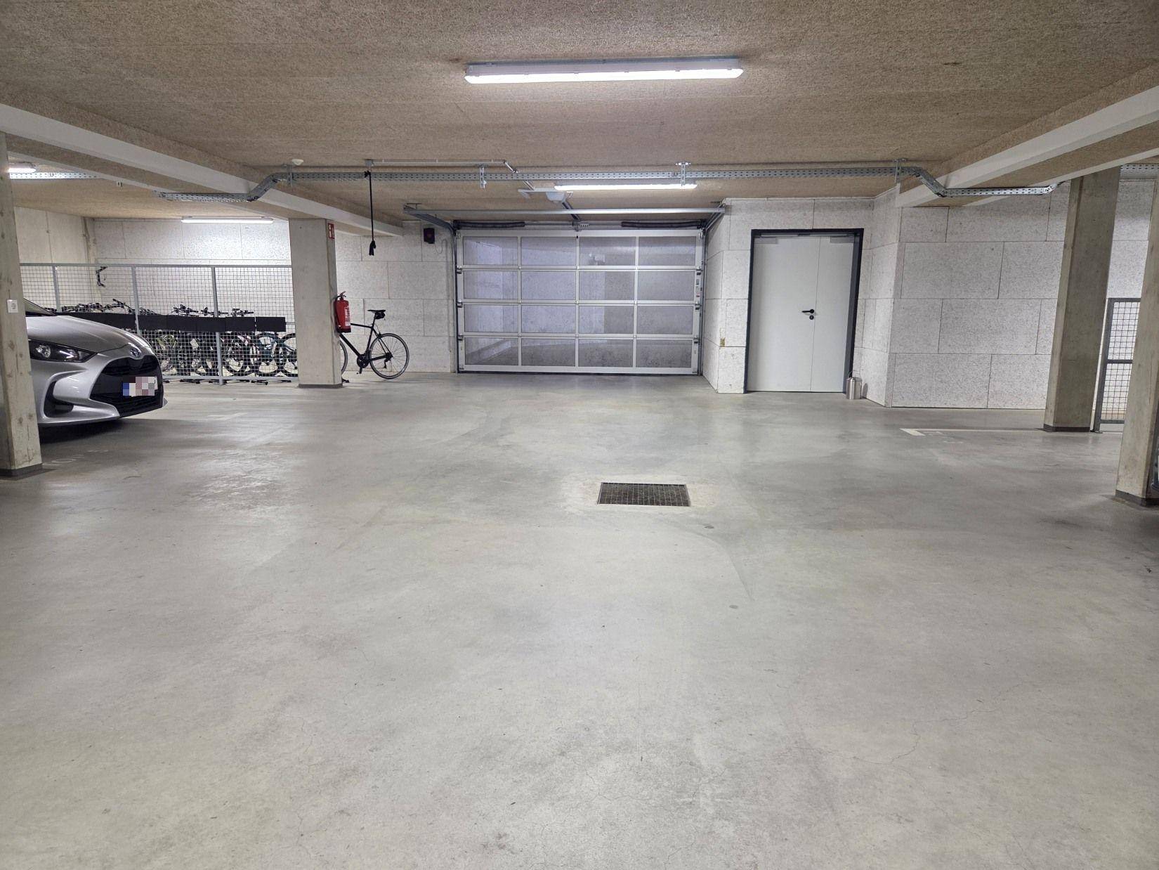Geräumige Tiefgarage mit Rolltor und separatem Zugang, bietet viel Platz für Fahrzeuge und Fahrräder.