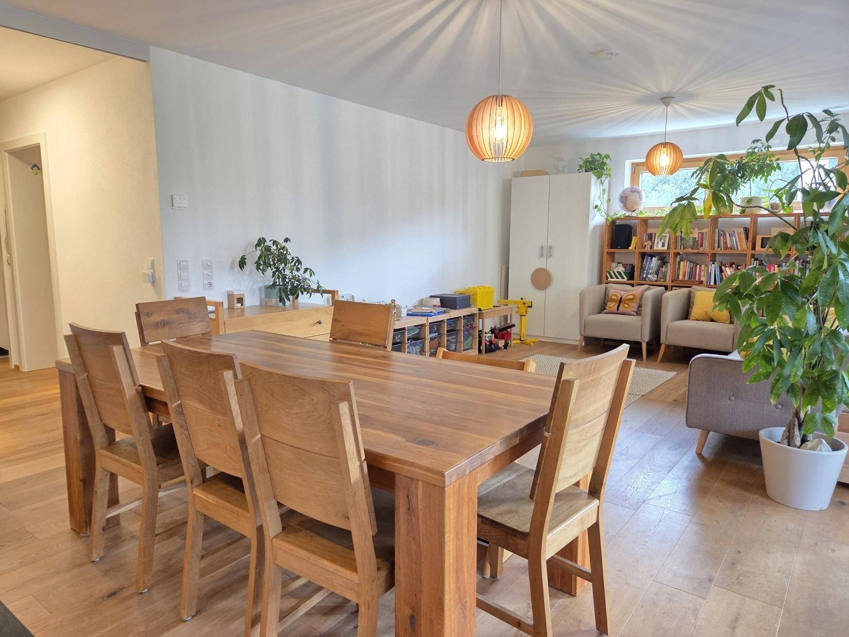 Geräumiger Wohn-Essbereich mit großem Holztisch und Blick auf den Wohnbereich.