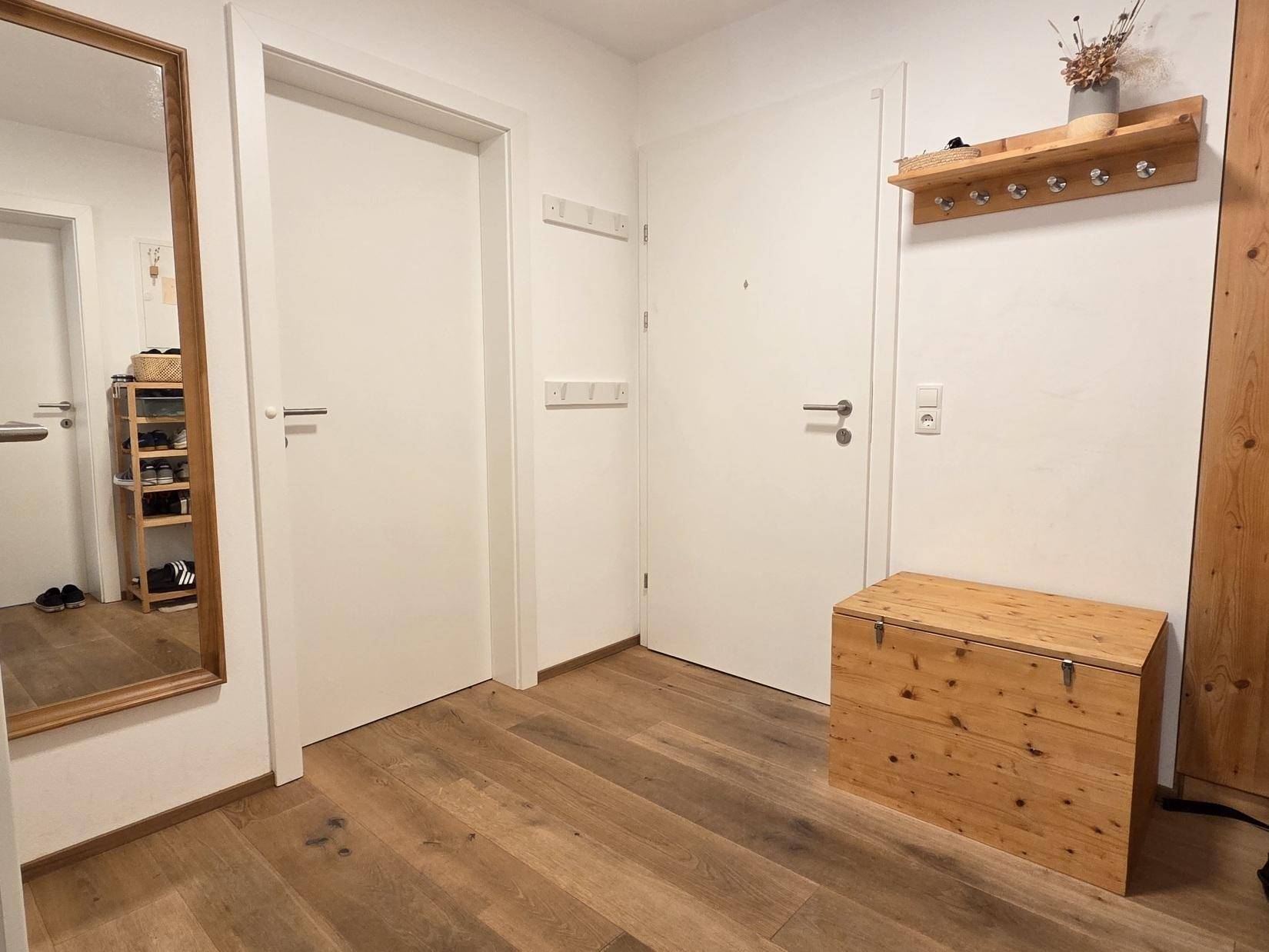 Heller Flur mit Holzboden, Garderobe und Spiegel, einladend gestaltet.