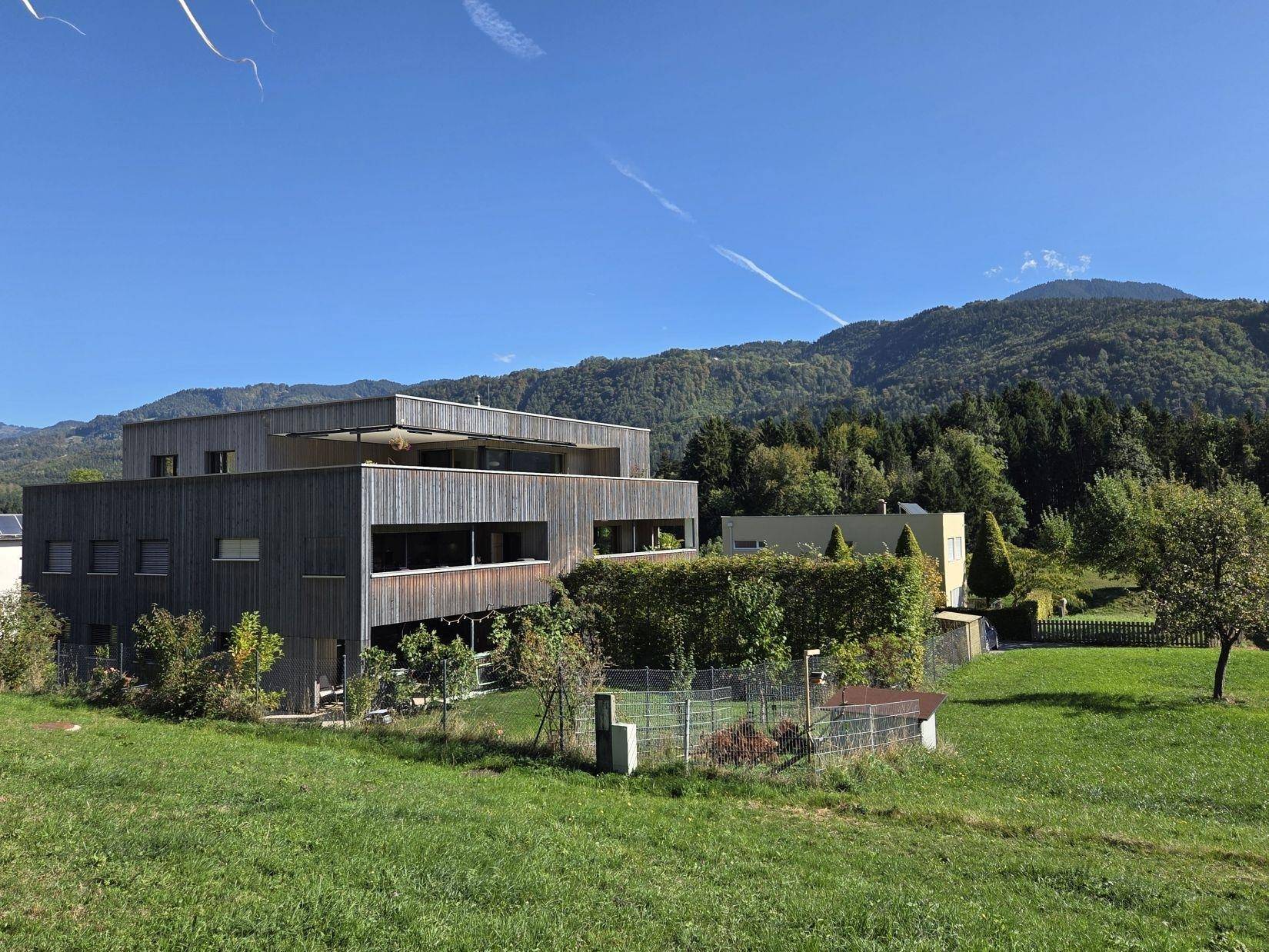 Modernes Gebäude mit Holzfassade und weitem Blick auf die umliegende Berglandschaft.