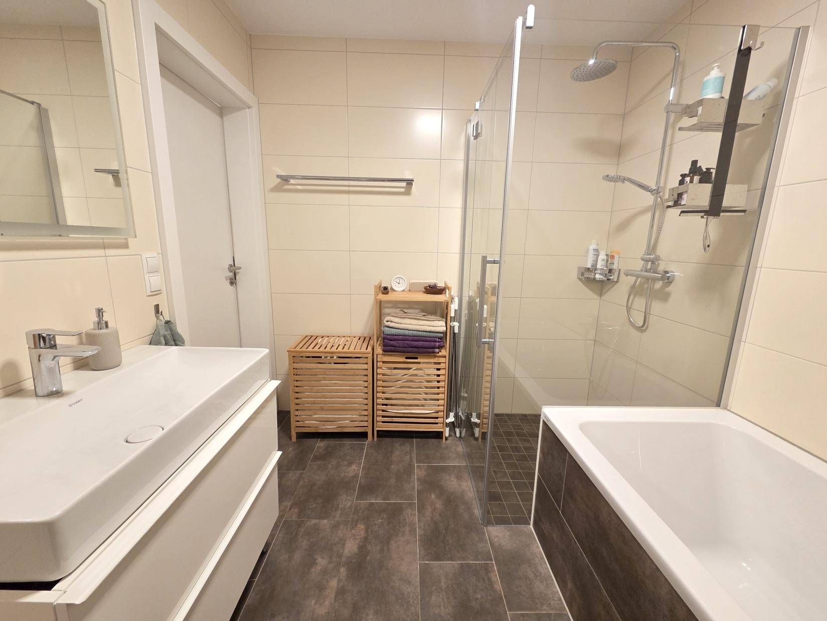 Geräumiges Badezimmer mit Badewanne, Duschkabine und modernem Waschbecken.