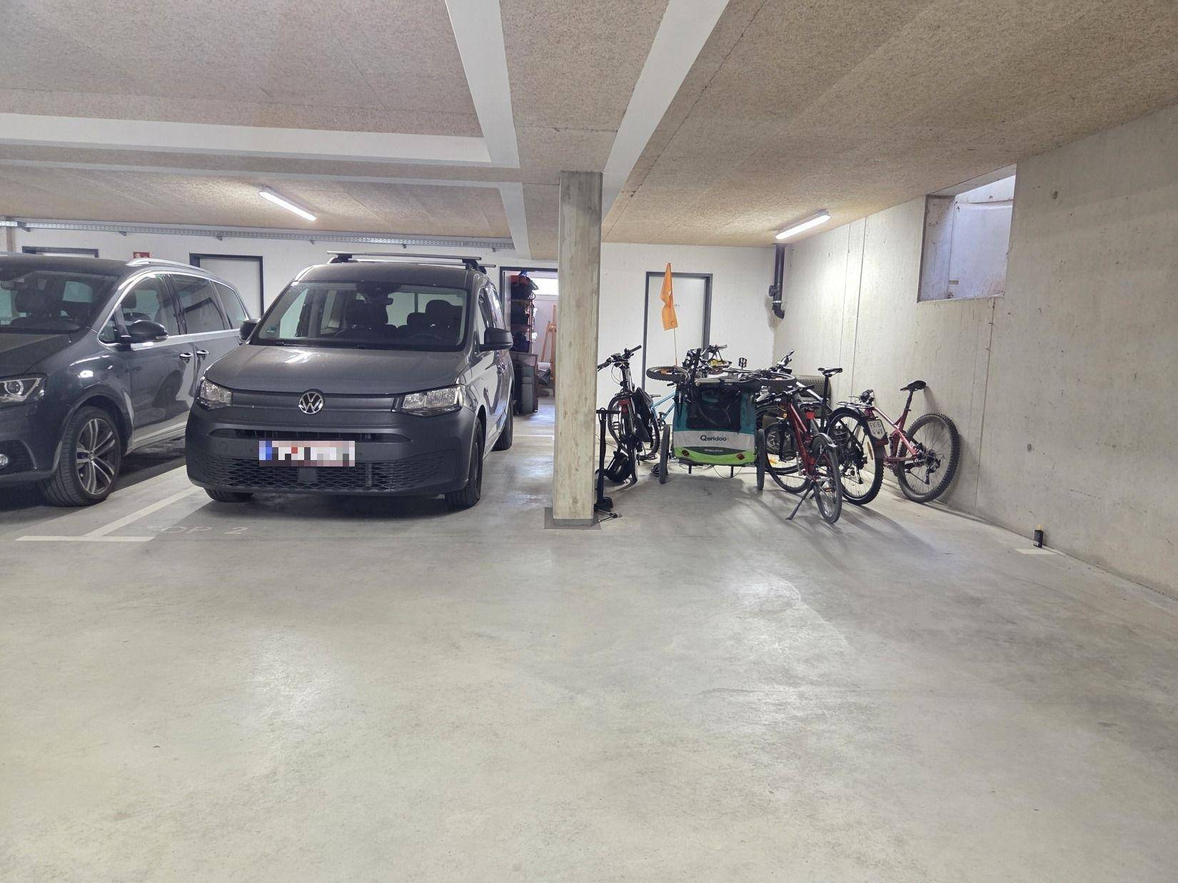 Tiefgarage mit geparkten Autos und Fahrrädern, bietet sicheren Stellplatz und Abstellmöglichkeiten.