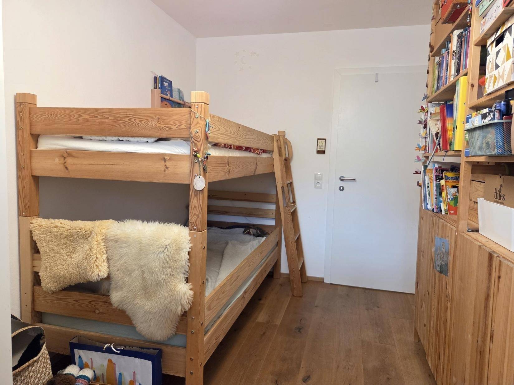 Kinderzimmer mit Etagenbett aus Holz und Bücherregal, ideal für Geschwister.