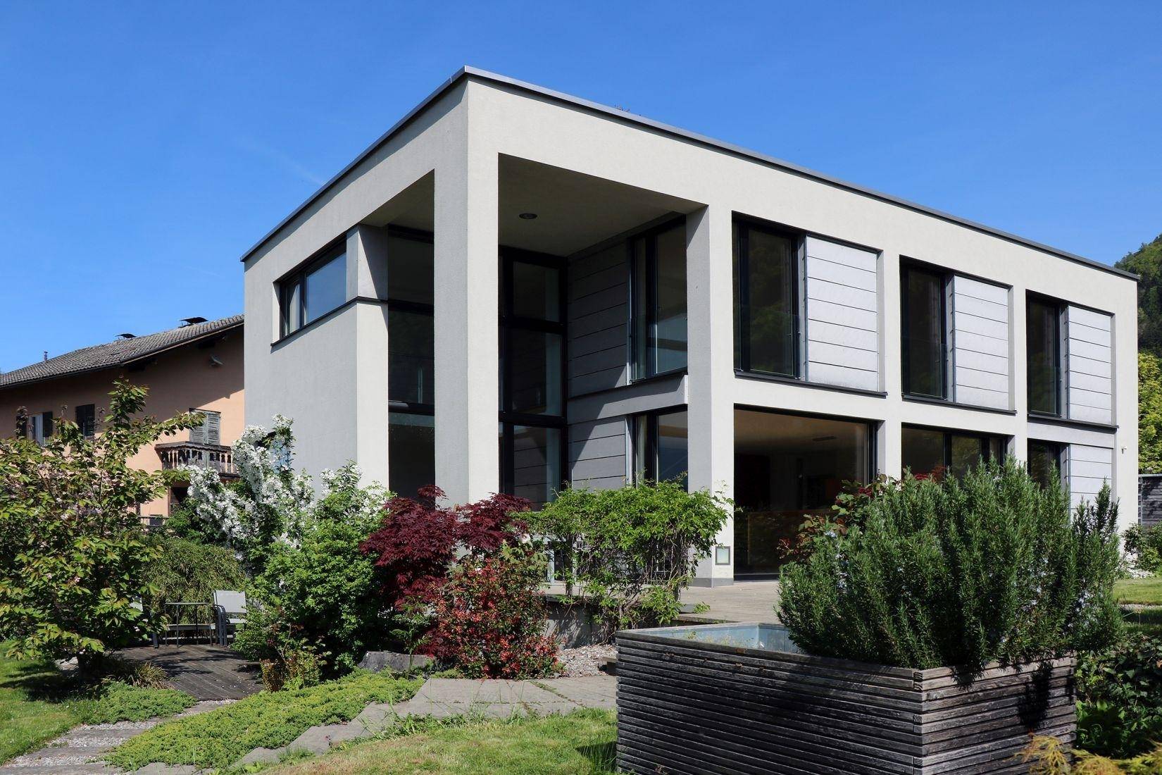 Moderne Architektur des Hauses mit klaren Linien, großen Fenstern und gepflegtem Vorgarten.