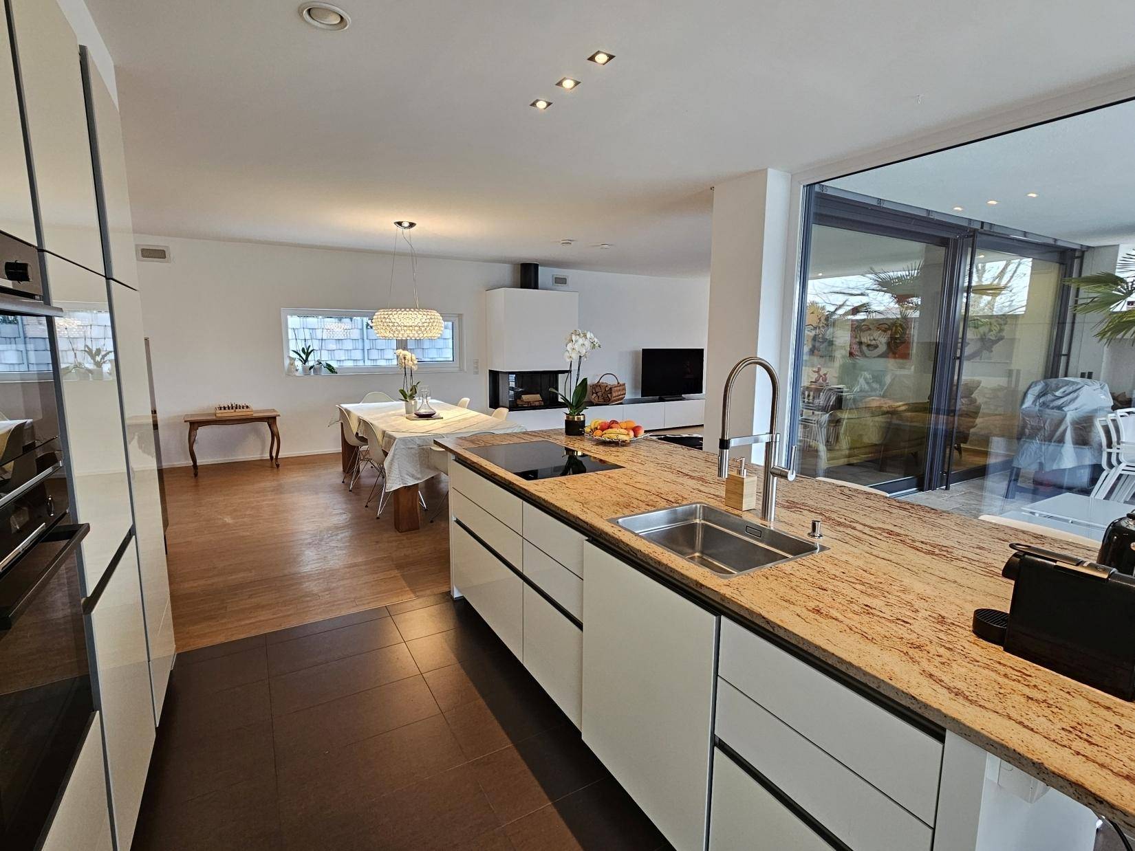 Offene Küche mit Kücheninsel und Blick auf den Ess- und Wohnbereich mit Kamin.