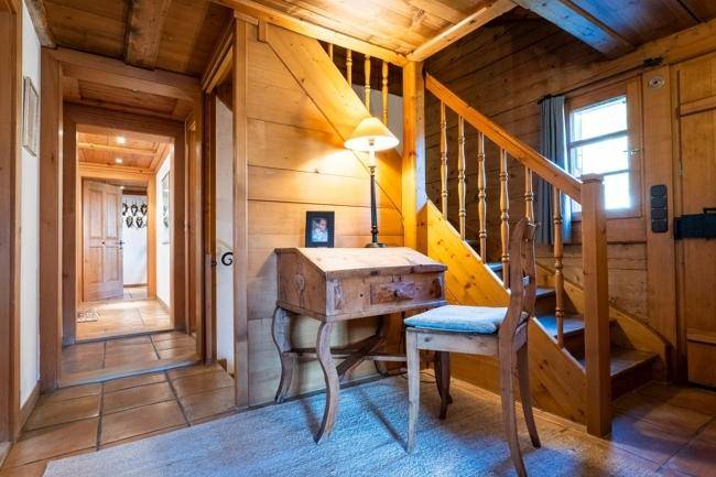 Traditioneller Flur mit Holzvertäfelung, Treppe und einem kleinen Schreibtisch, der eine gemütliche Atmosphäre schafft.