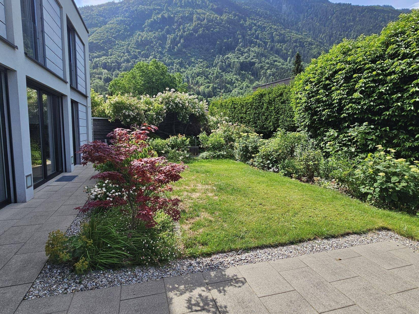 Gepflegte Rasenfläche mit angrenzender Terrasse und einem malerischen Bergblick.