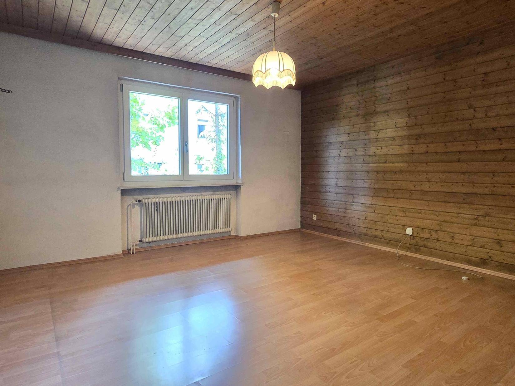 Schlafzimmer mit Holzwand, Holzdecke und Laminatboden, ideal für individuelle Einrichtung.