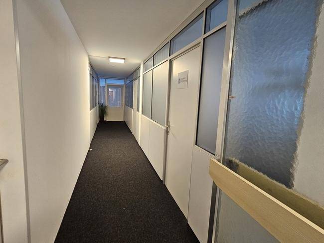 Heller Bürogang mit Teppichboden, weißen Wänden und Türen mit Milchglas-Elementen.