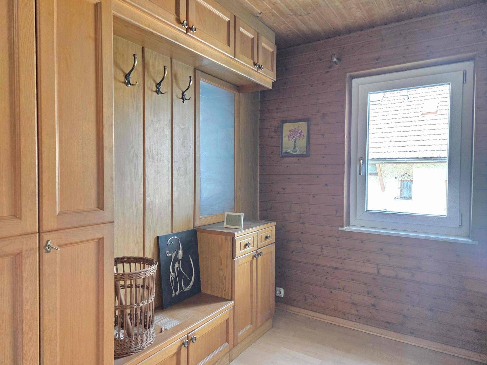 Flur mit Einbauschränken aus Holz, Holzdecke und Fenster, bietet viel Stauraum.
