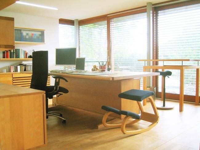 Geräumiges Büro mit großem Schreibtisch, ergonomischem Stuhl und großen Fenstern für viel Tageslicht.