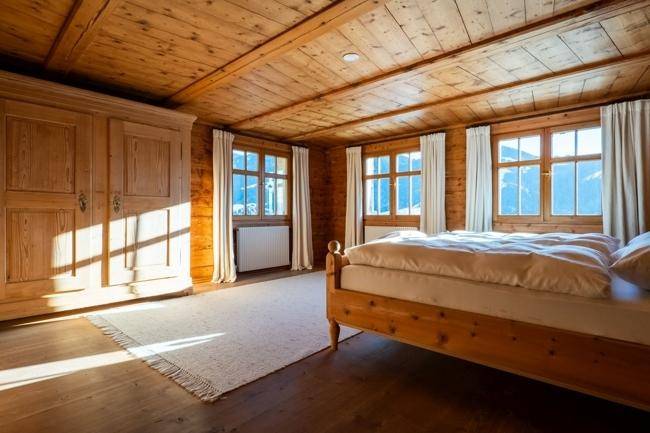 Geräumiges Schlafzimmer mit Holzwänden, großem Kleiderschrank und mehreren Fenstern, die viel Licht hereinlassen.