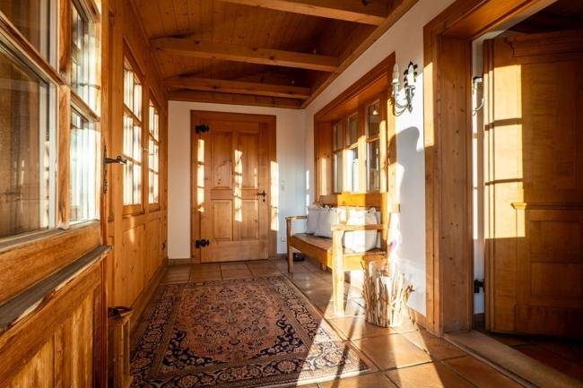Heller Eingangsbereich mit Holzbalkendecke, Fliesenboden und traditioneller Holzbank.