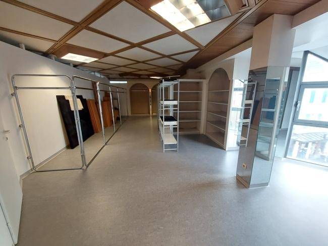 Lagerraum oder Werkstatt mit grauem Boden, Holzdeckenverkleidung und Regalsystemen.