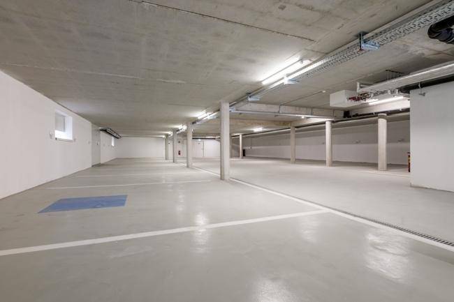 Weitläufige Tiefgarage mit vielen Stellplätzen und sauberem Betonboden.