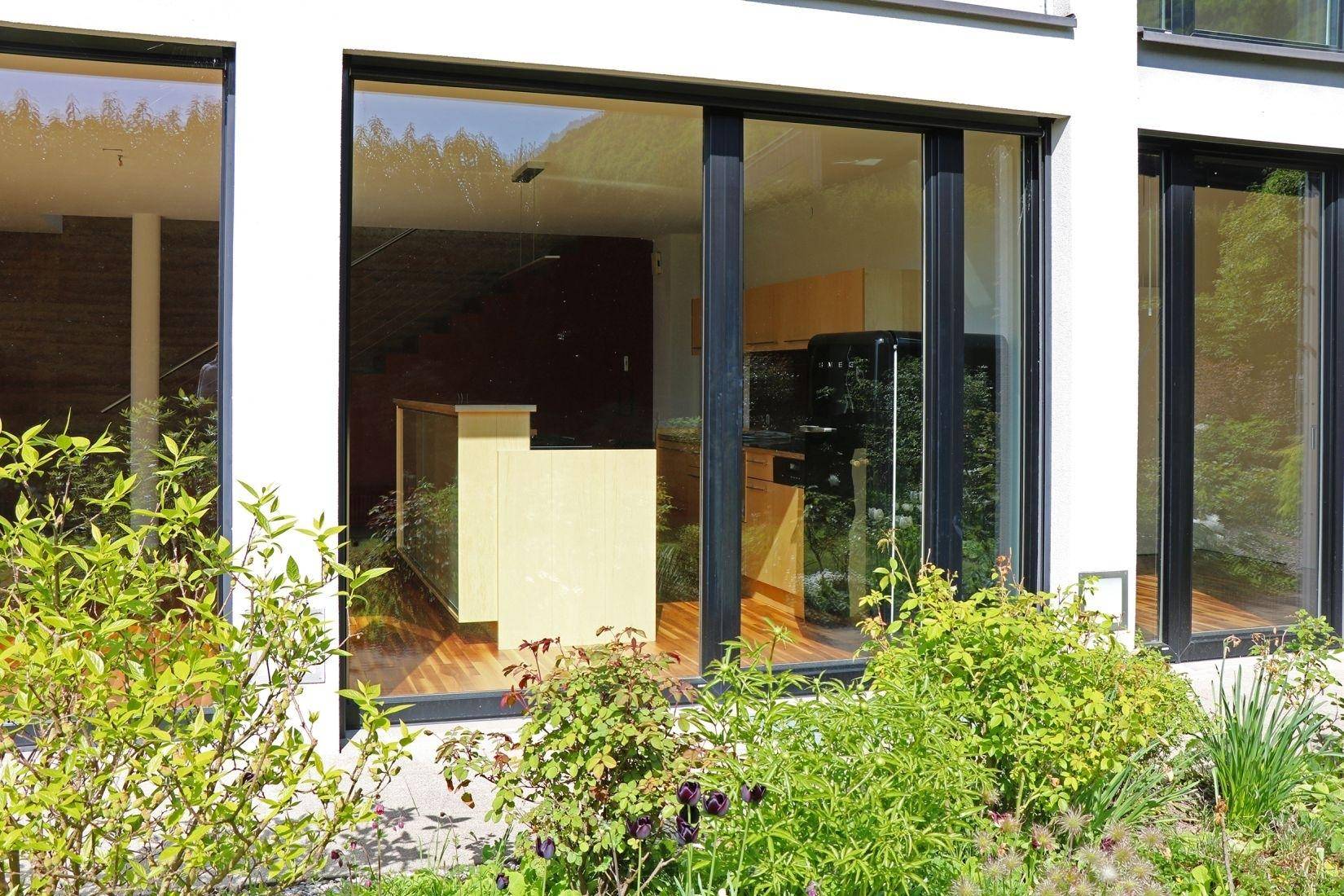 Große Fensterfronten des Hauses mit Blick auf den Innenbereich und die umgebende Natur.