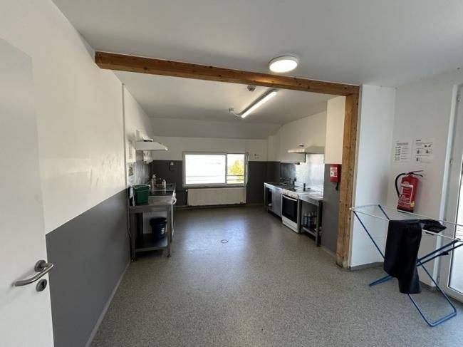 Geräumige Gemeinschaftsküche mit Edelstahleinrichtungen und einem Holzbalken an der Decke.