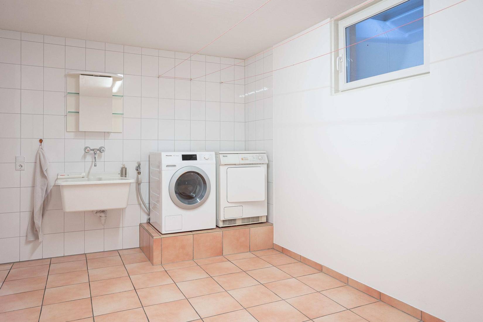 Praktischer Waschraum mit Waschmaschine, Trockner und Waschbecken.
